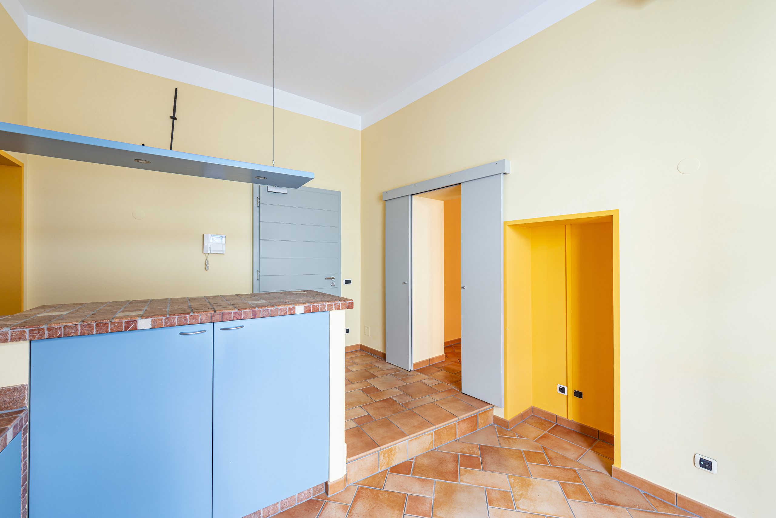 Heller Eingangsbereich mit Terrakottafliesen und farbigen Einbauten