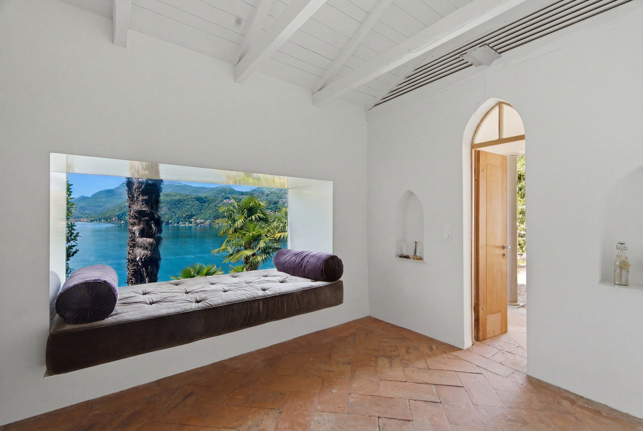 Heller Raum mit Terrakottaboden und Sitznische mit Seeblick