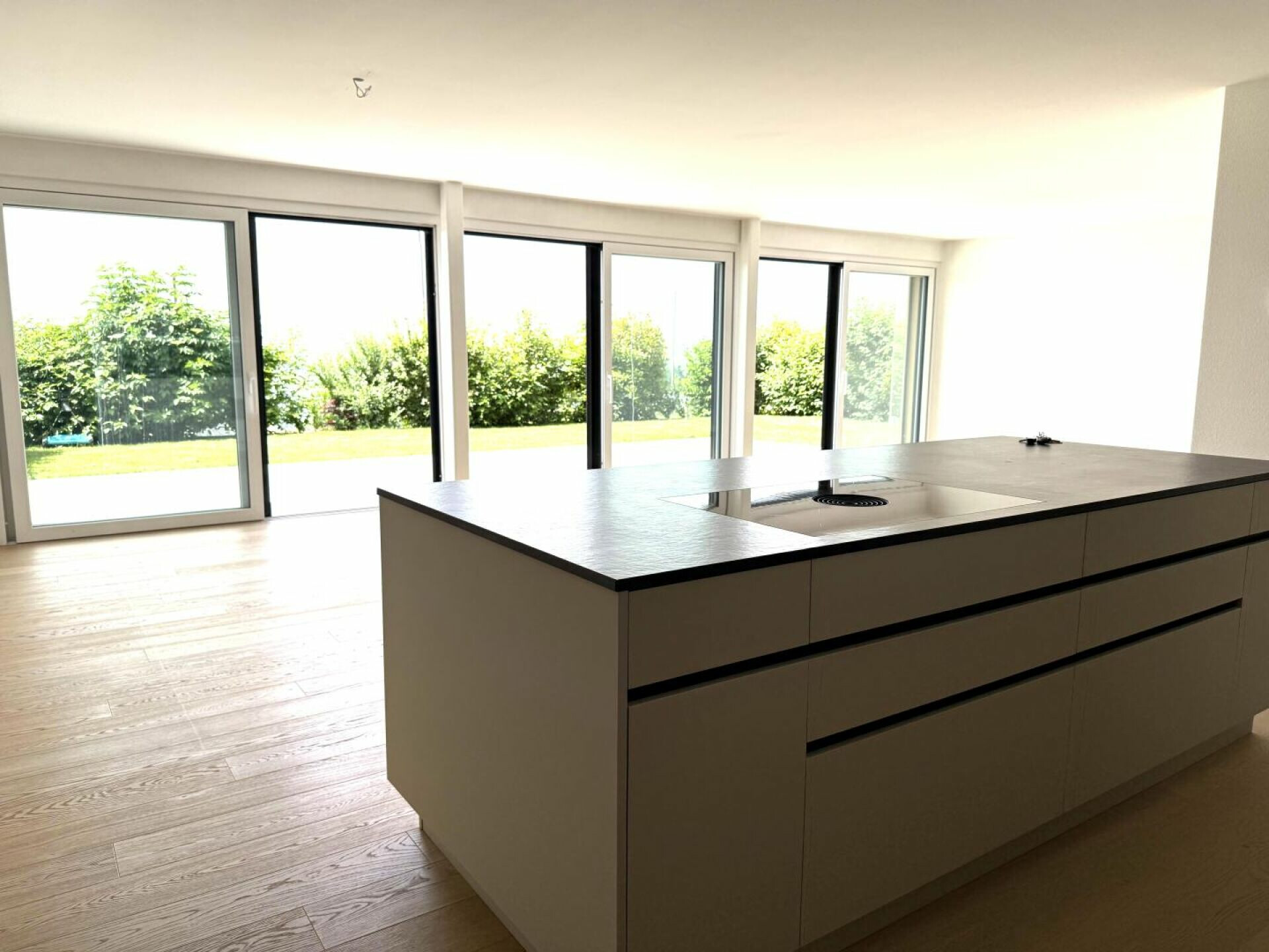 Moderne offene Küche mit Kochinsel und großen Fenstern