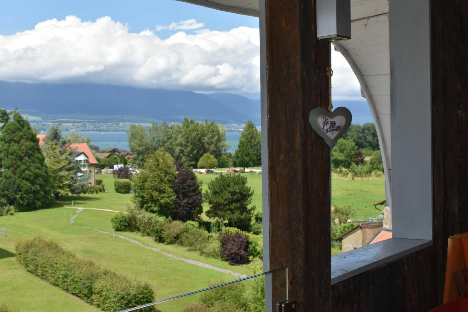 Blick von einem Balkon auf See, Wiesen und Berge