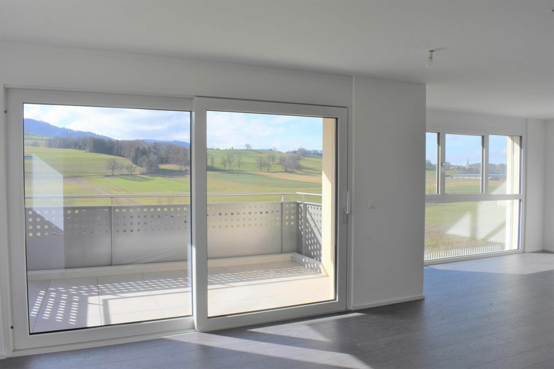 Helle Wohnfläche mit großflächigen Fenstern und Balkon