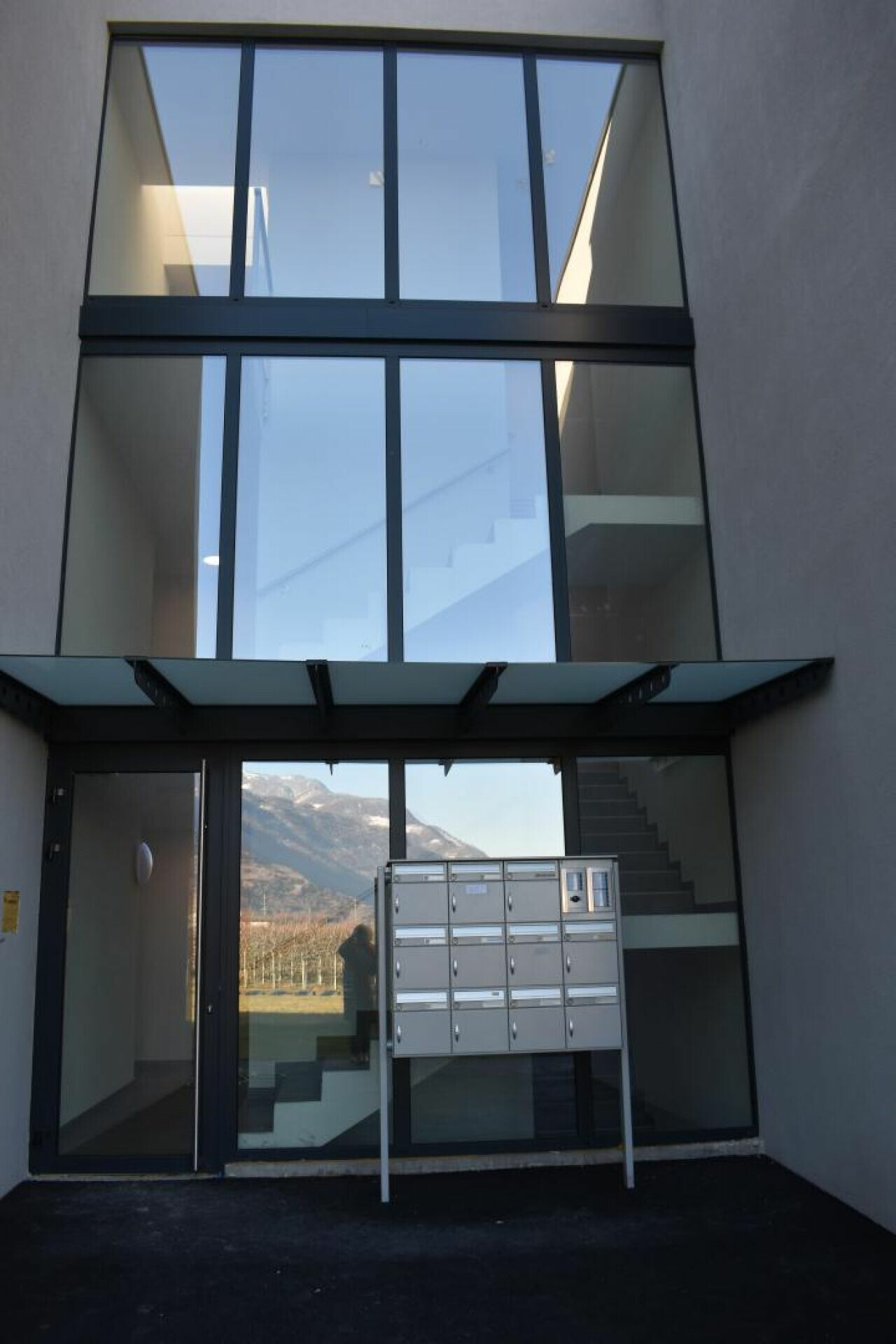 Moderner Innenhof mit großer Verglasung und Briefkastenanlage