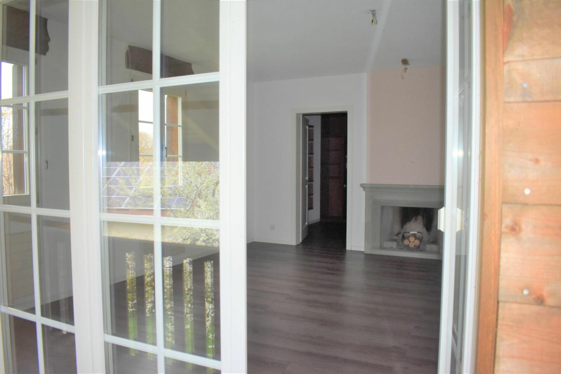 Heller Wohnraum mit Kamin und Balkonzugang