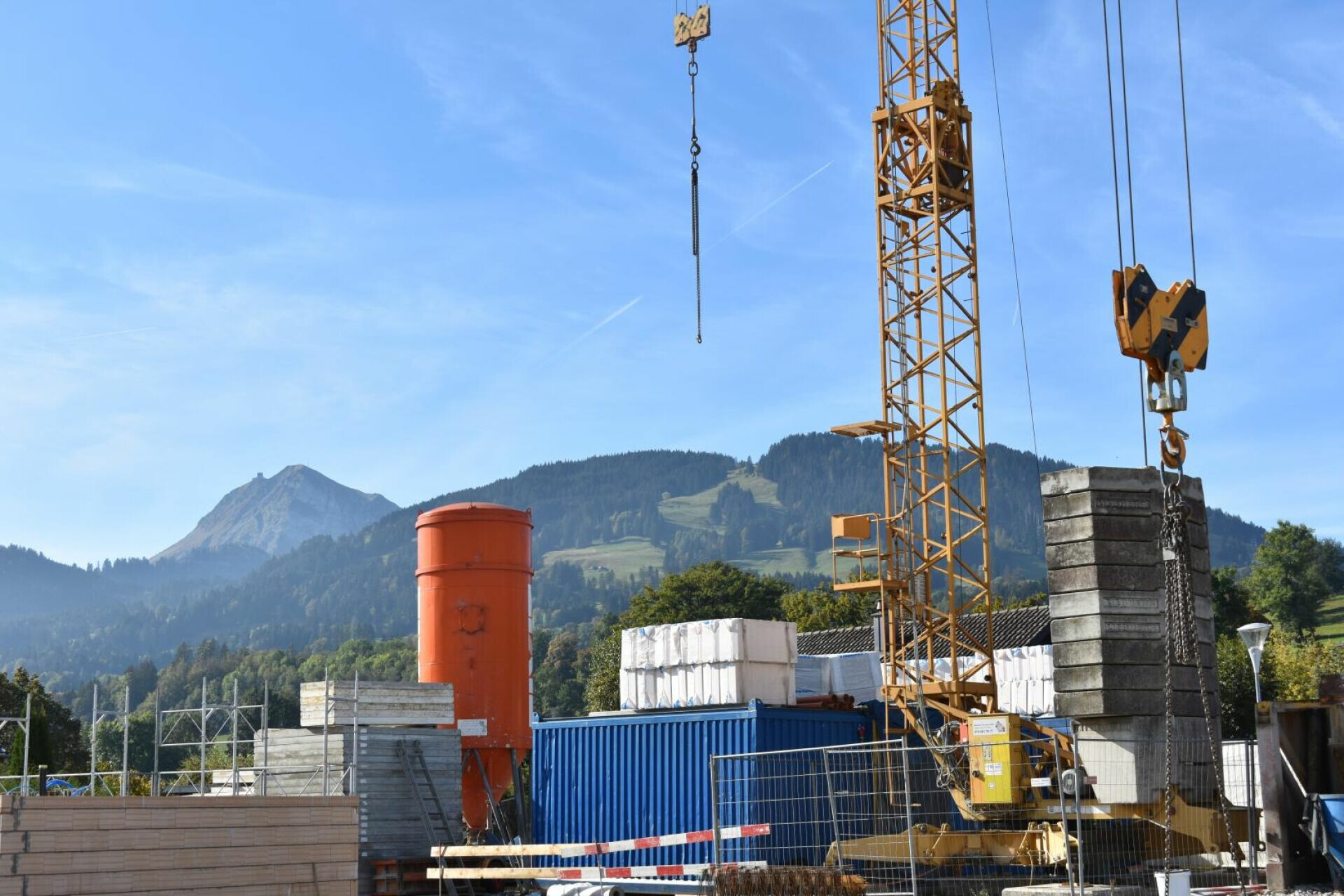 Baustelle mit Kran vor Bergkulisse
