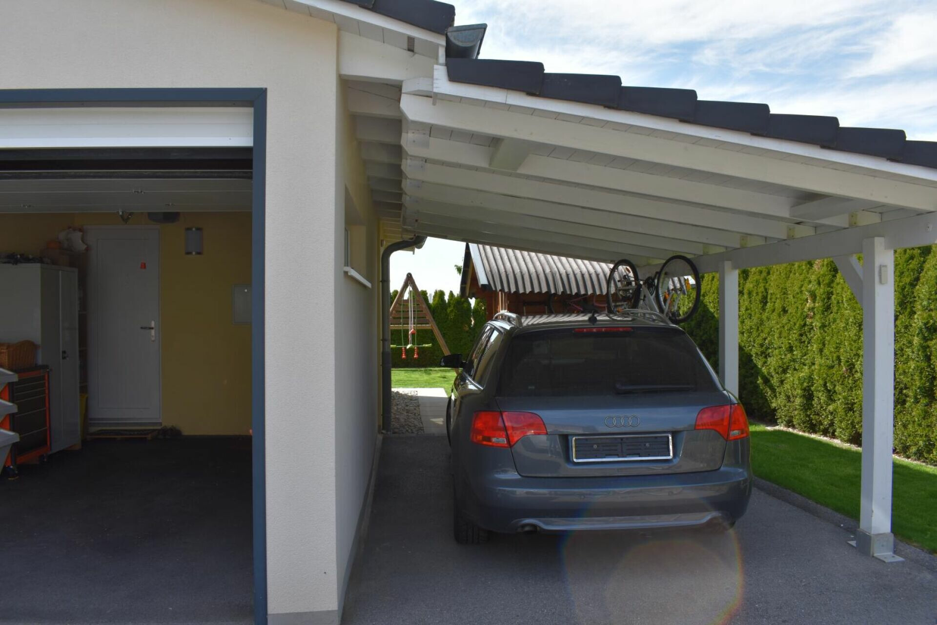 Carport mit geparktem Kombi neben Garage