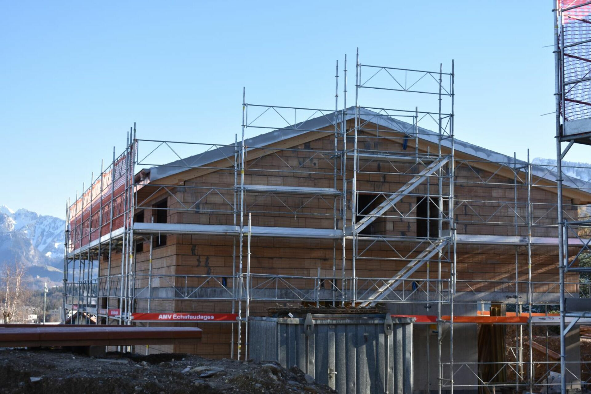Baugerüst um ein Holzgebäude mit Bergkulisse