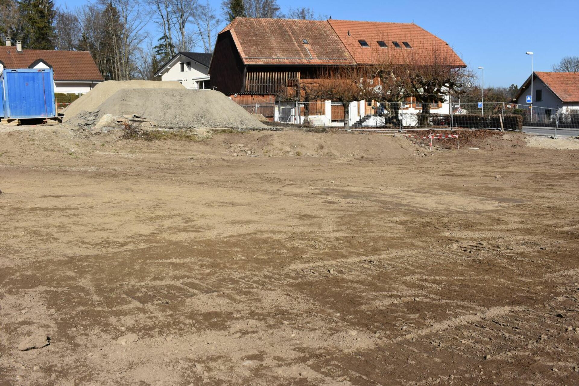 Baustelle mit freier Erdfläche vor Wohnhäusern