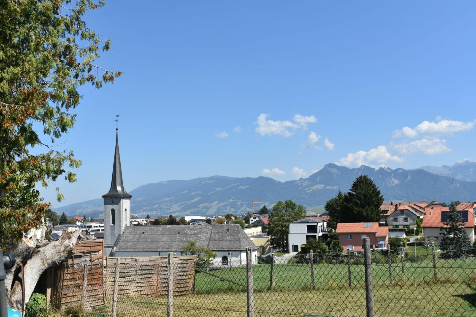 Landschaft mit Dorfkirche und Bergpanorama