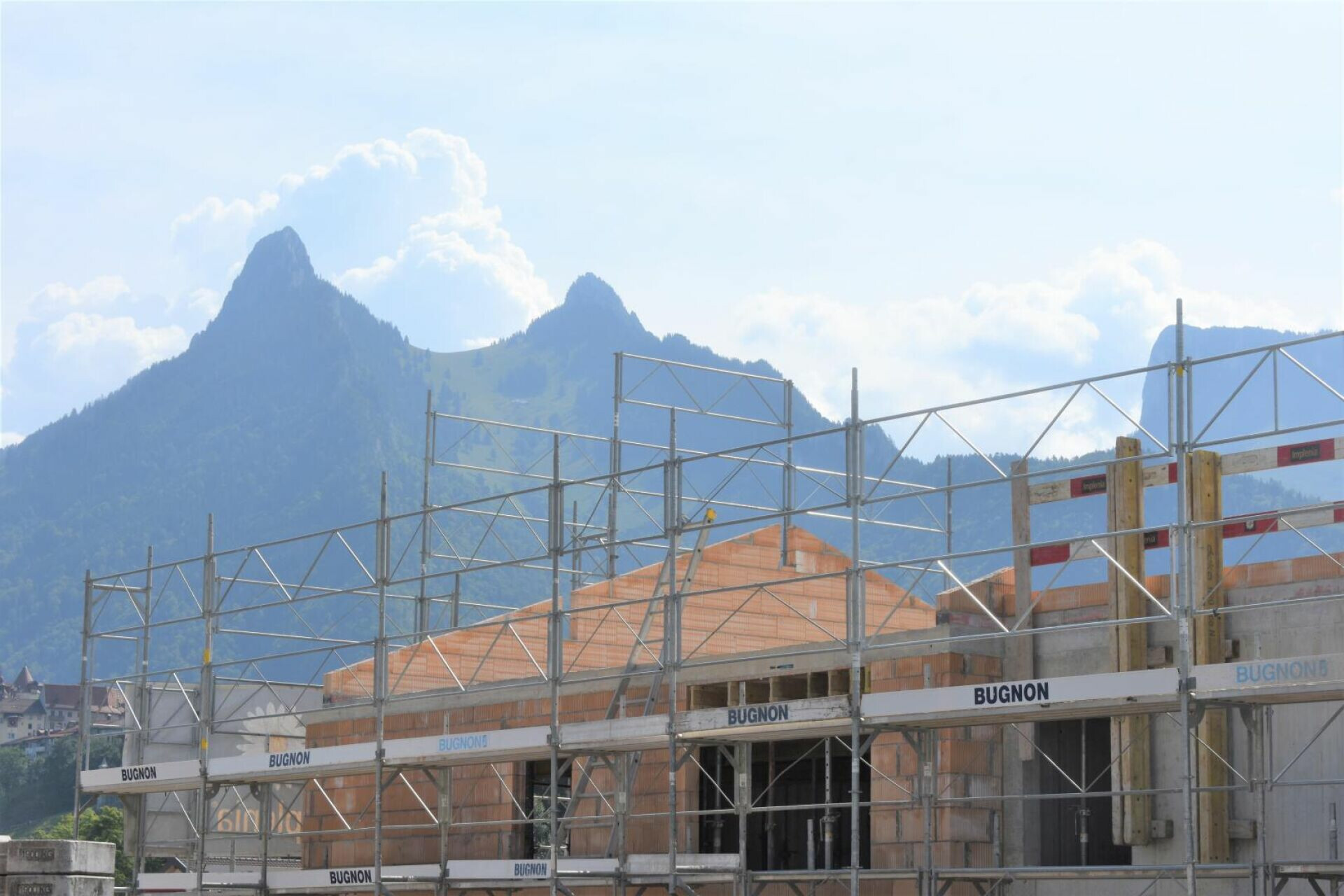 Gebäude im Bau mit Gerüst vor Bergkulisse