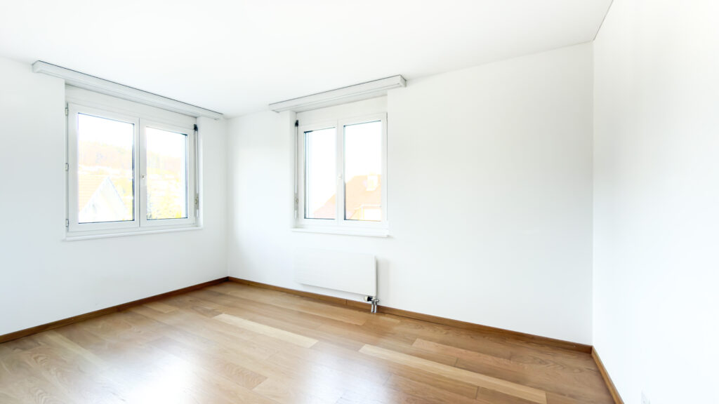 Helles, leeres Zimmer mit zwei Fenstern