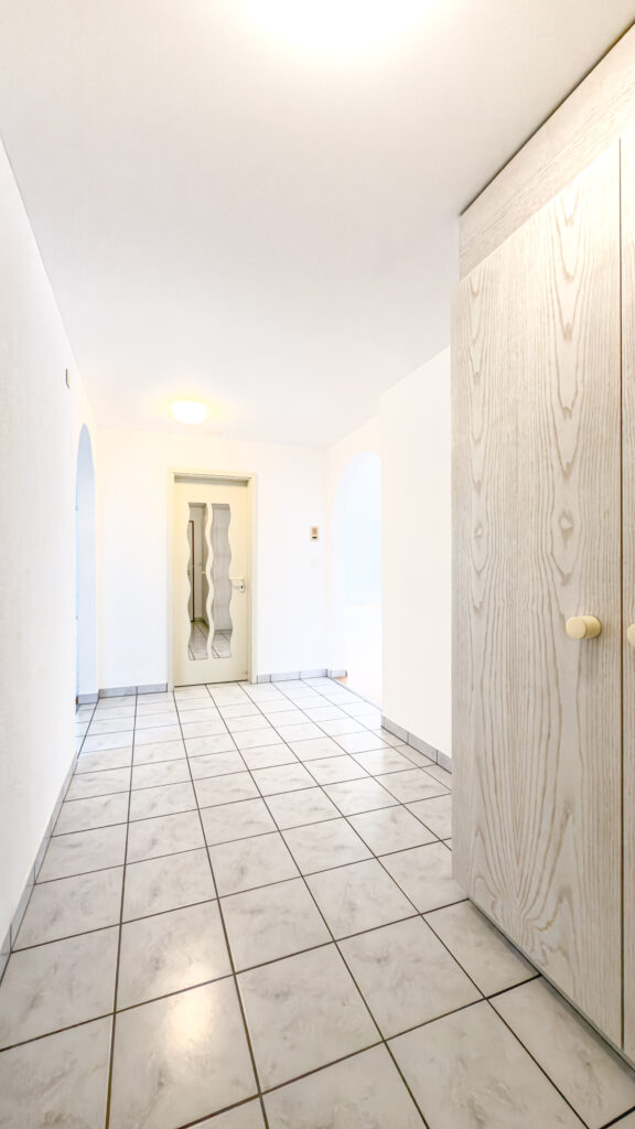 Heller Eingangsflur mit Fliesenboden und Holztür