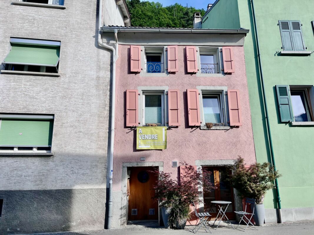 Pastellfarbene Hausfassade mit Verkaufsbanner
