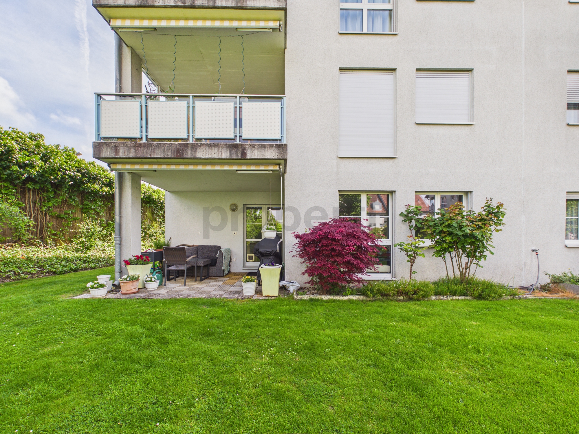Außenansicht eines Mehrfamilienhauses mit Balkon und Garten