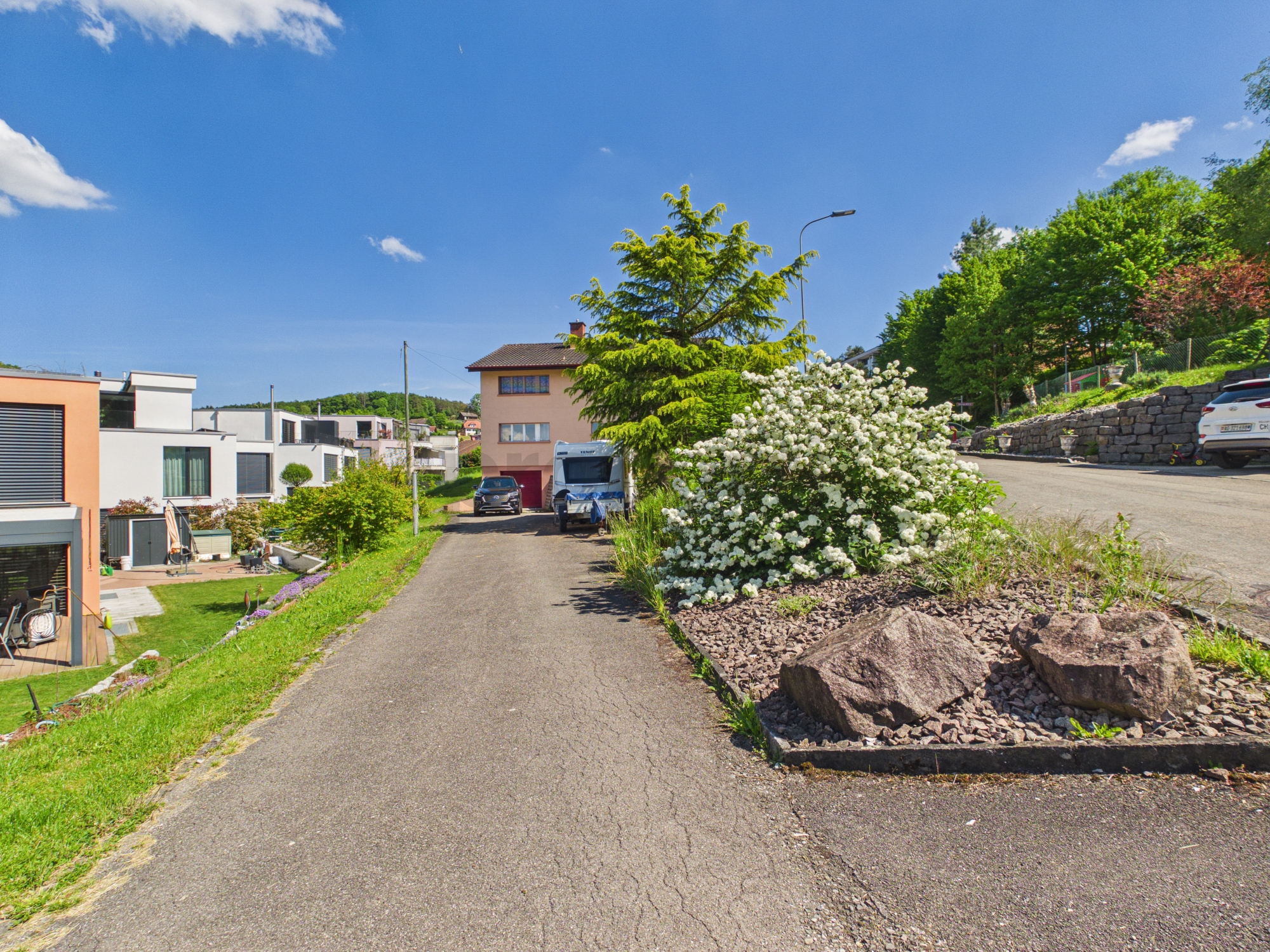 Wohnstraße mit Einfamilienhäusern und Gartenanlage