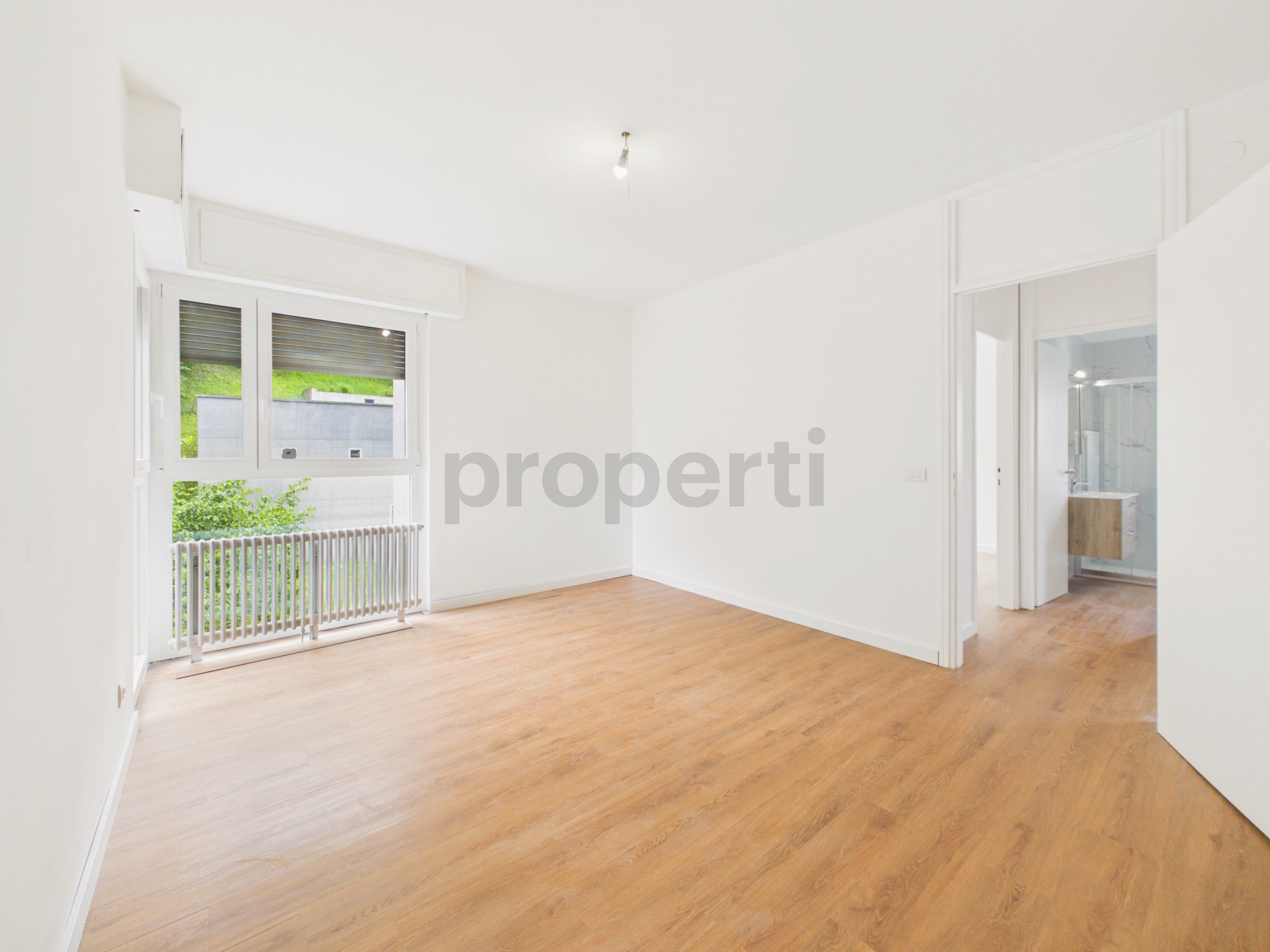 Leeres, helles Zimmer mit Holzoptikboden