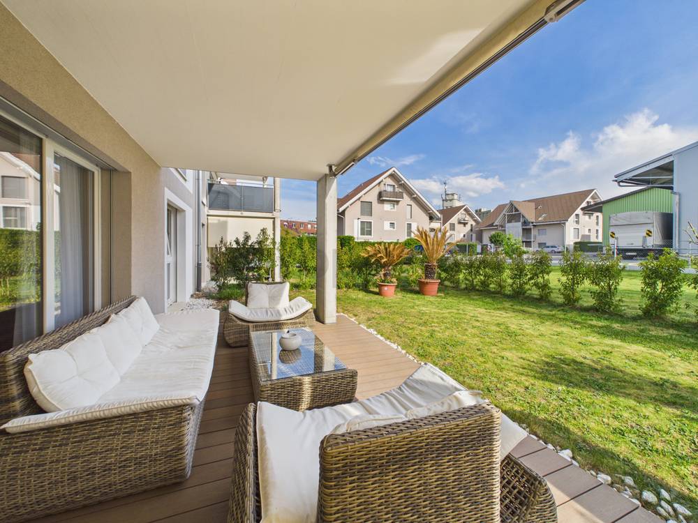 Überdachte Terrasse mit Lounge-Möbeln und Gartenblick