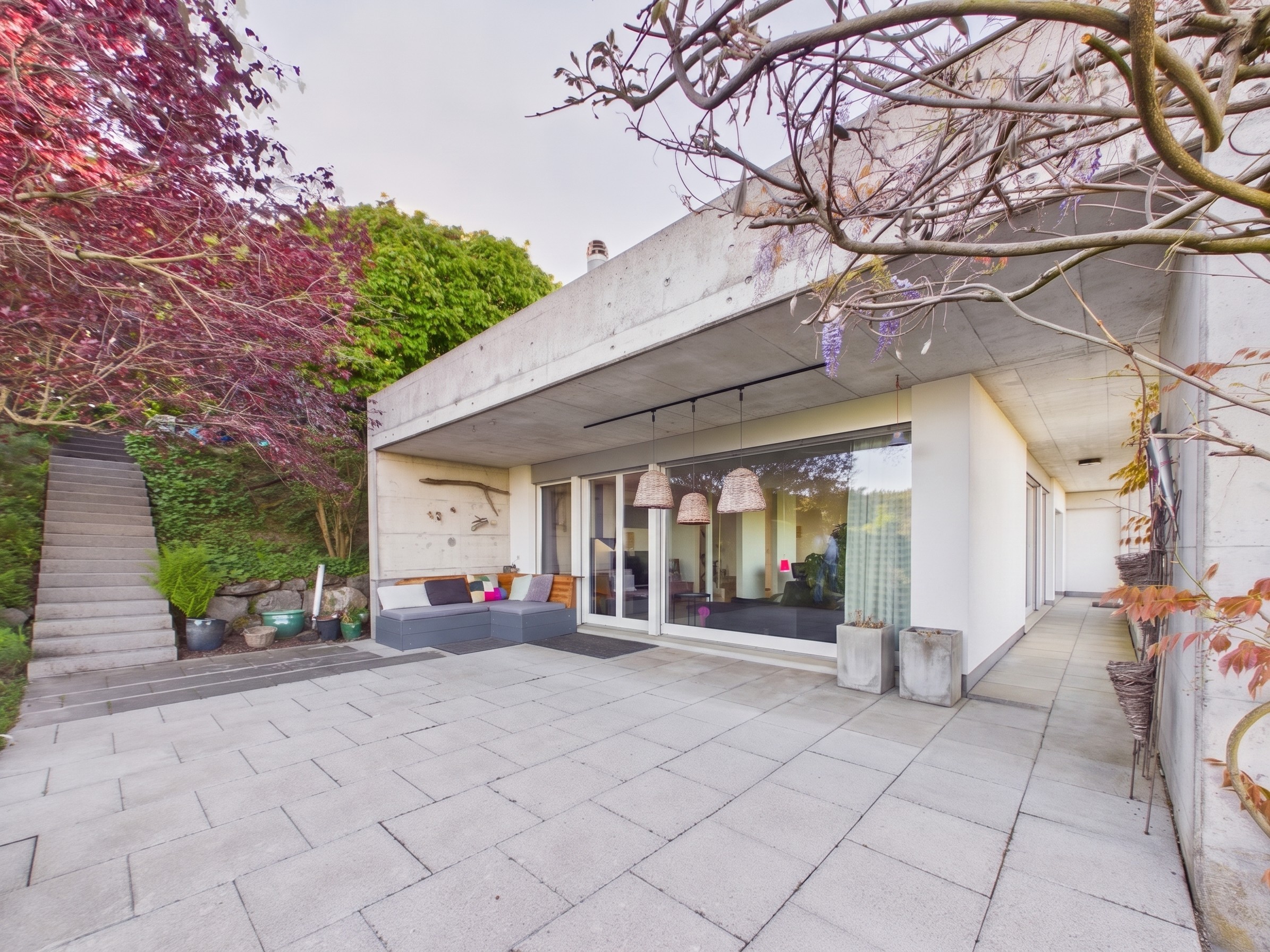 Moderner Patio mit Glasfront und Gartenhang