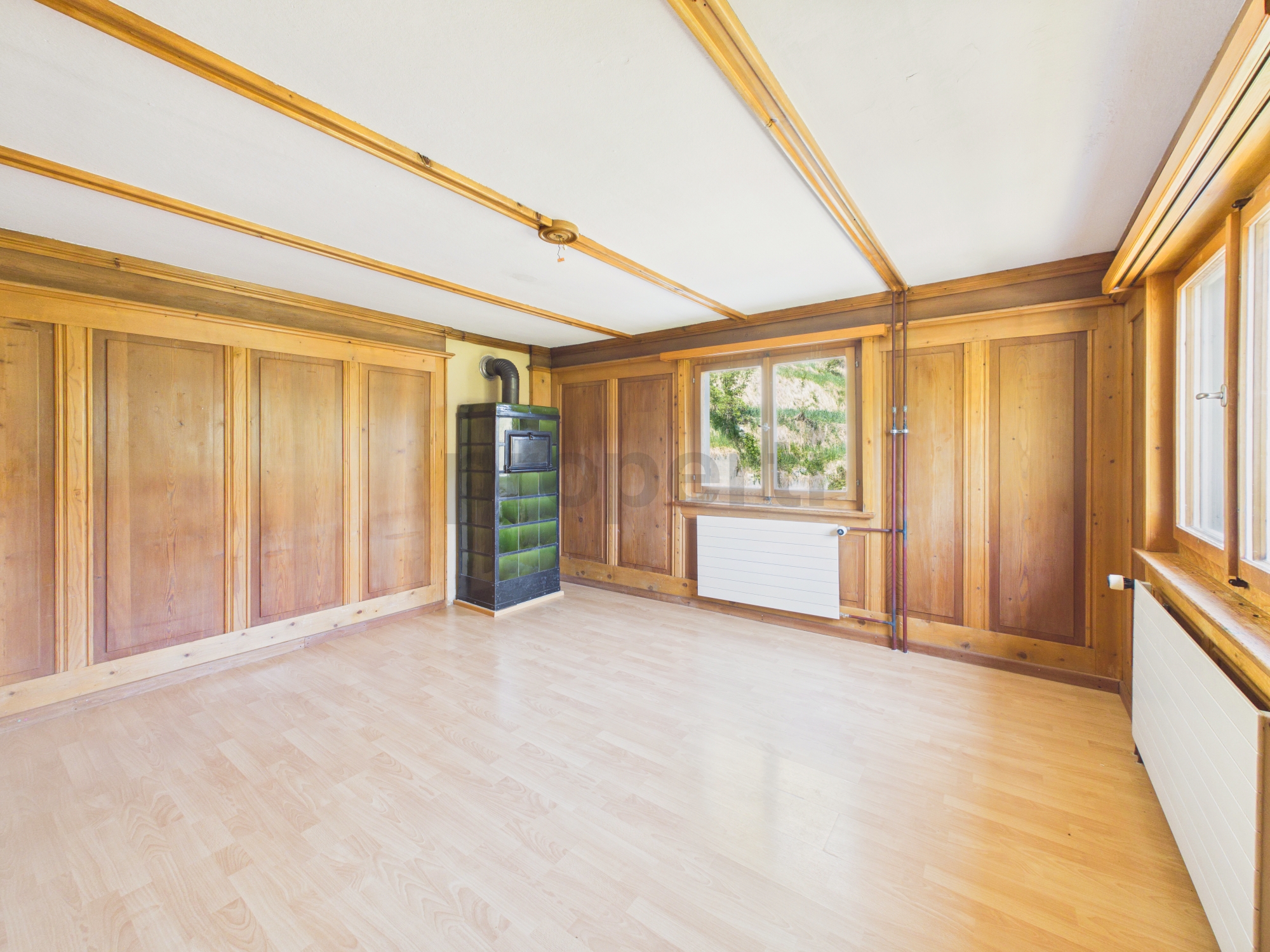 Heller Raum mit Holzverkleidung und Kaminofen