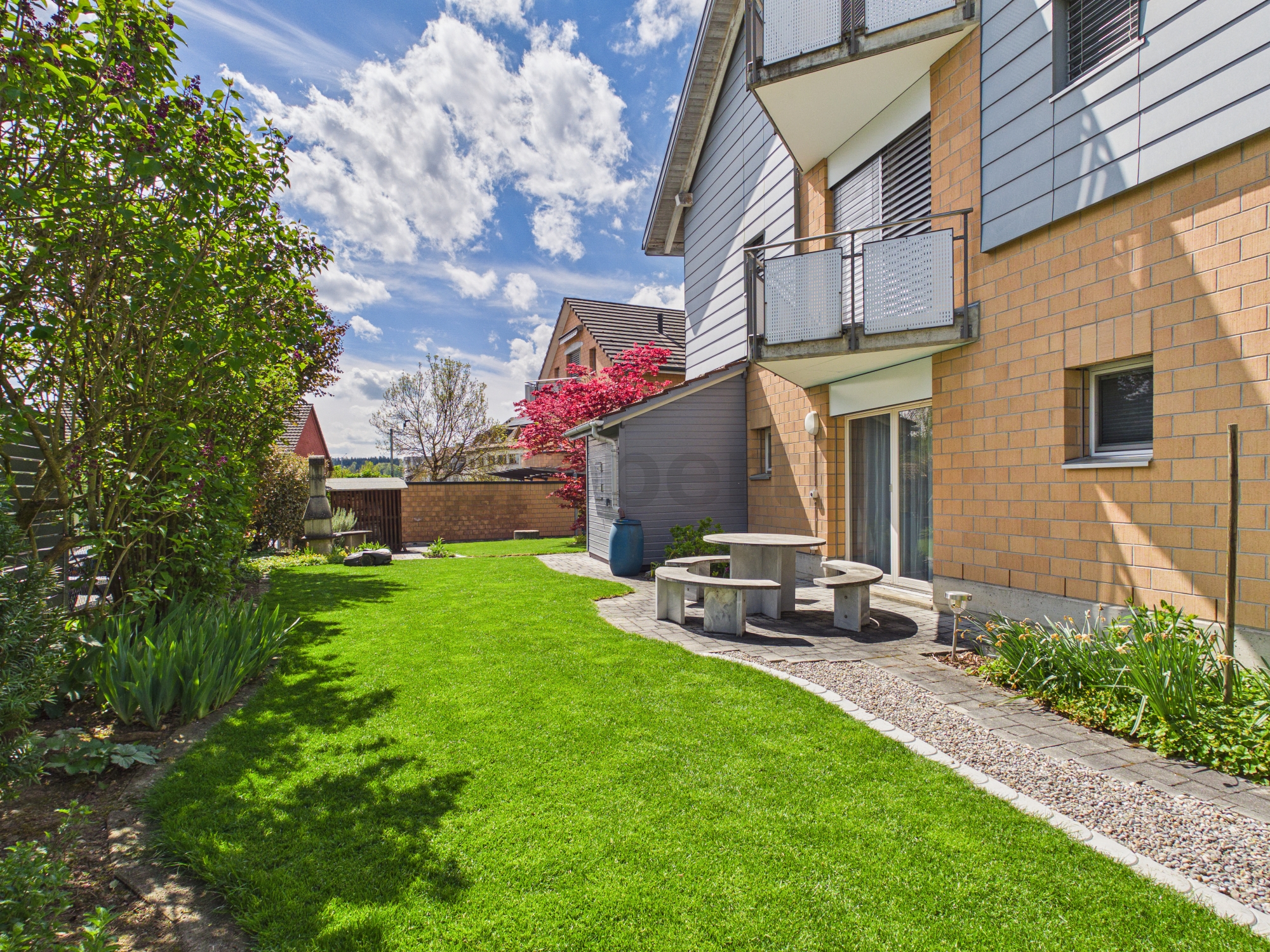 Gepflegter Garten mit Terrassenbereich am Mehrfamilienhaus