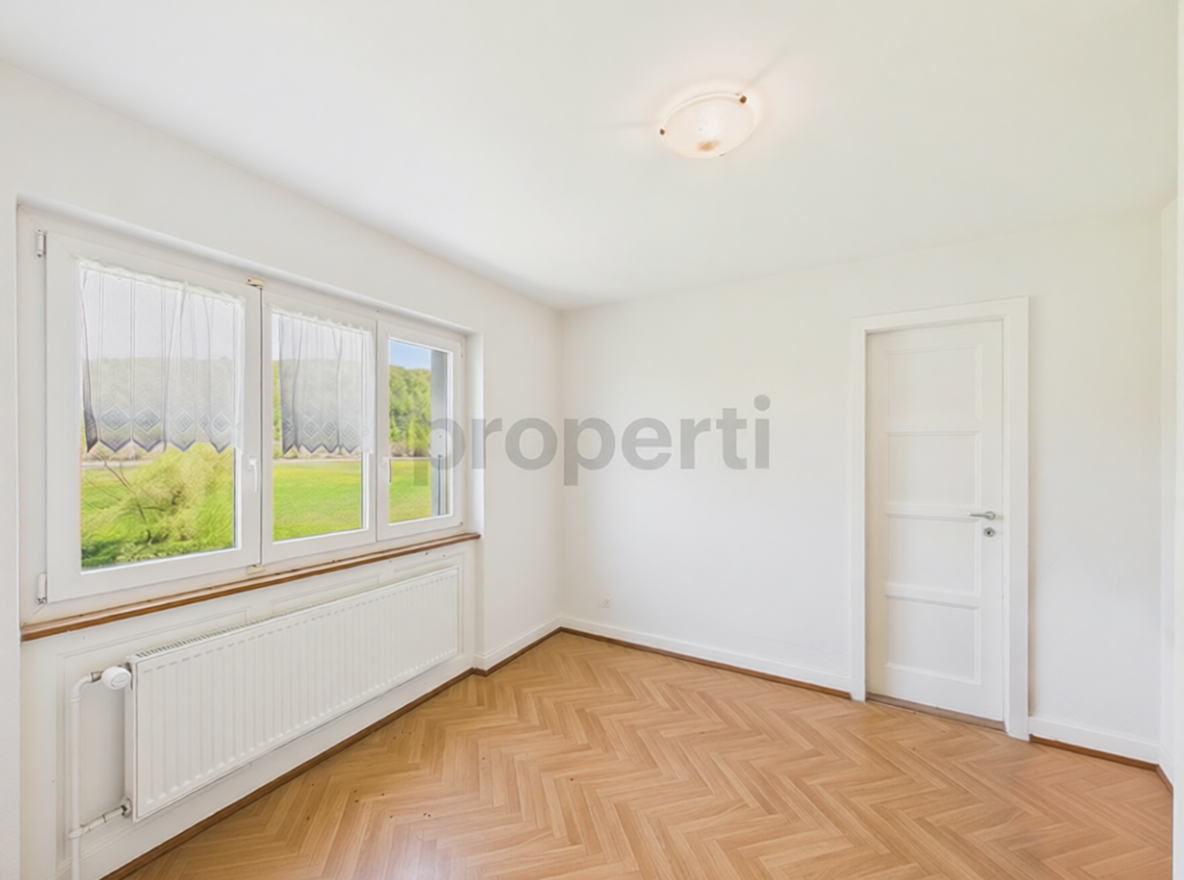 Helles, leeres Zimmer mit Fischgrätparkett und Fensterfront