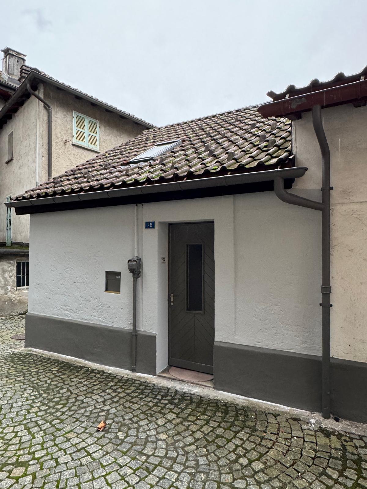 Außenansicht eines kleinen Hauses mit Ziegeldach und Eingang