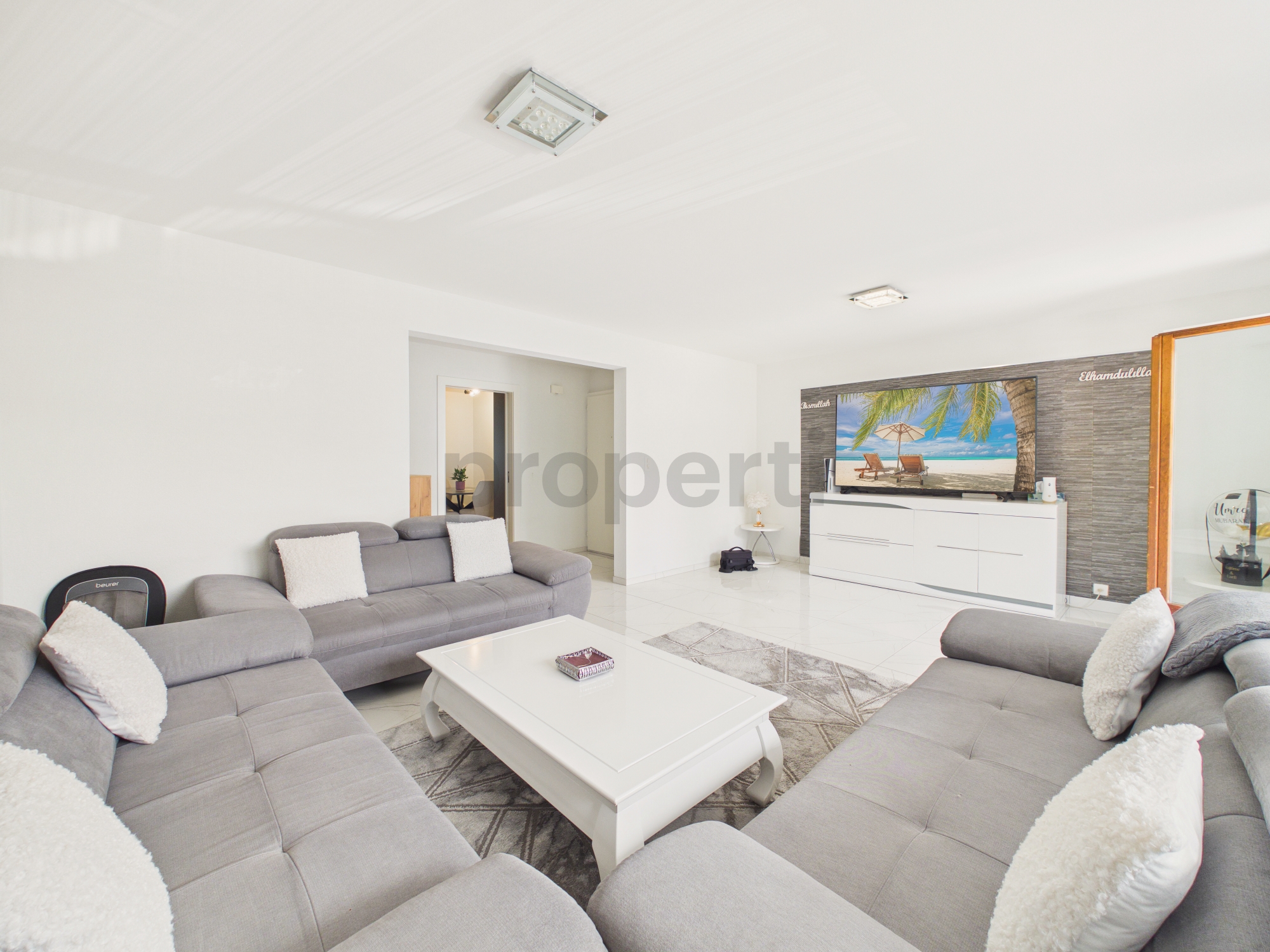 Helles Wohnzimmer mit grauer Sofalandschaft und TV-Wand