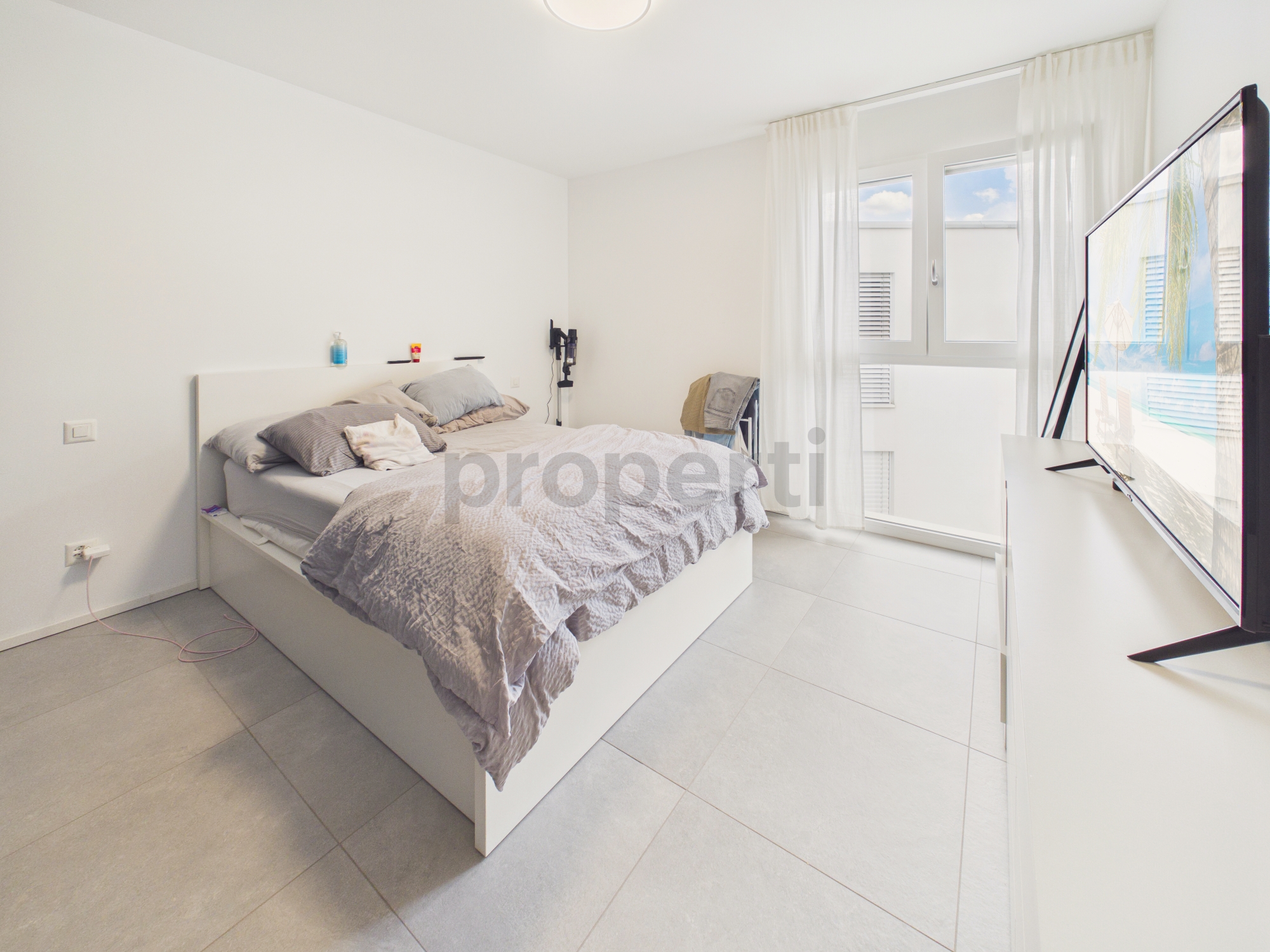 Helles Schlafzimmer mit großem Bett und Tageslichtfenster