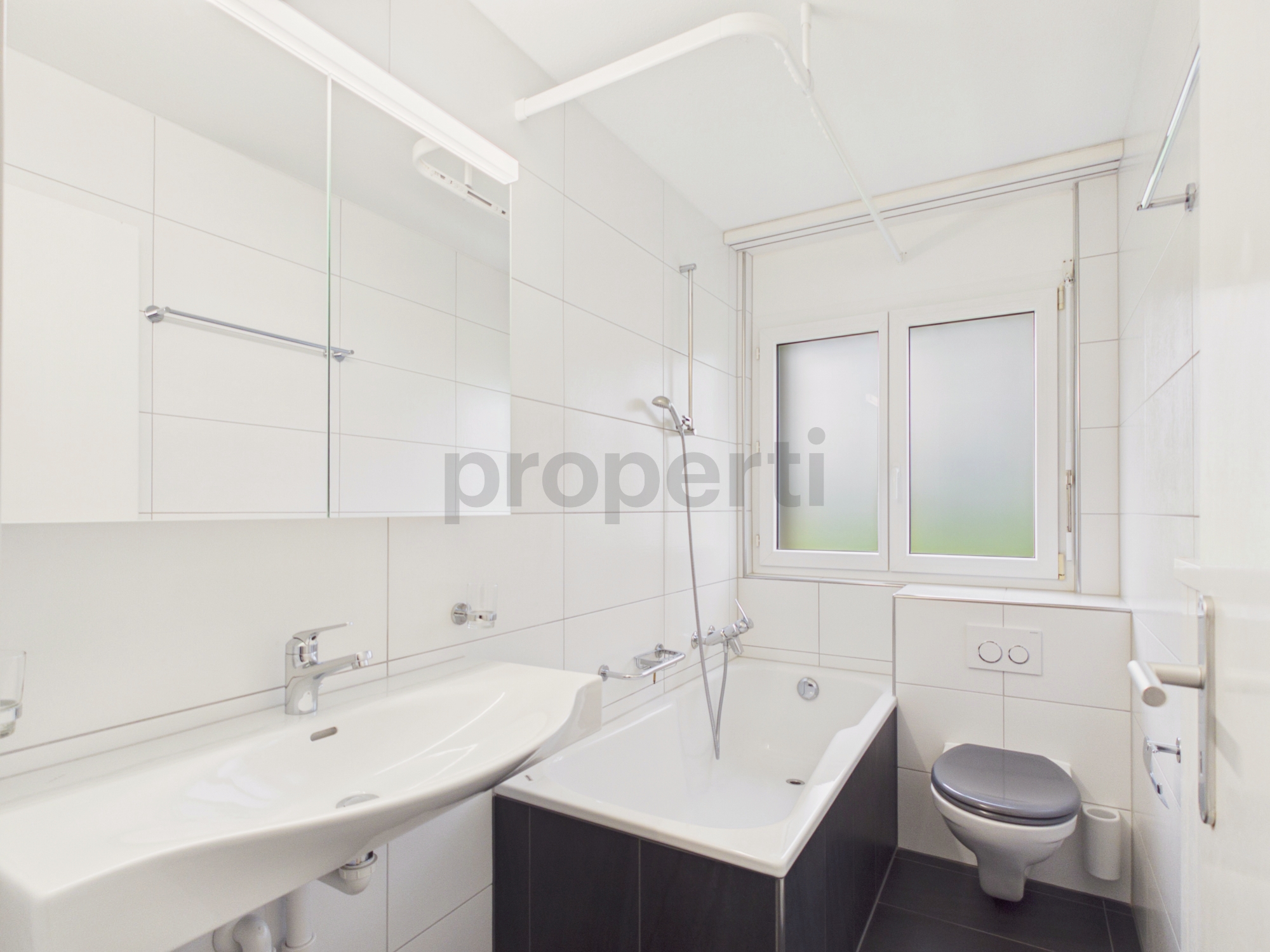 Kompaktes, modernes Badezimmer mit Badewanne, Waschbecken und WC