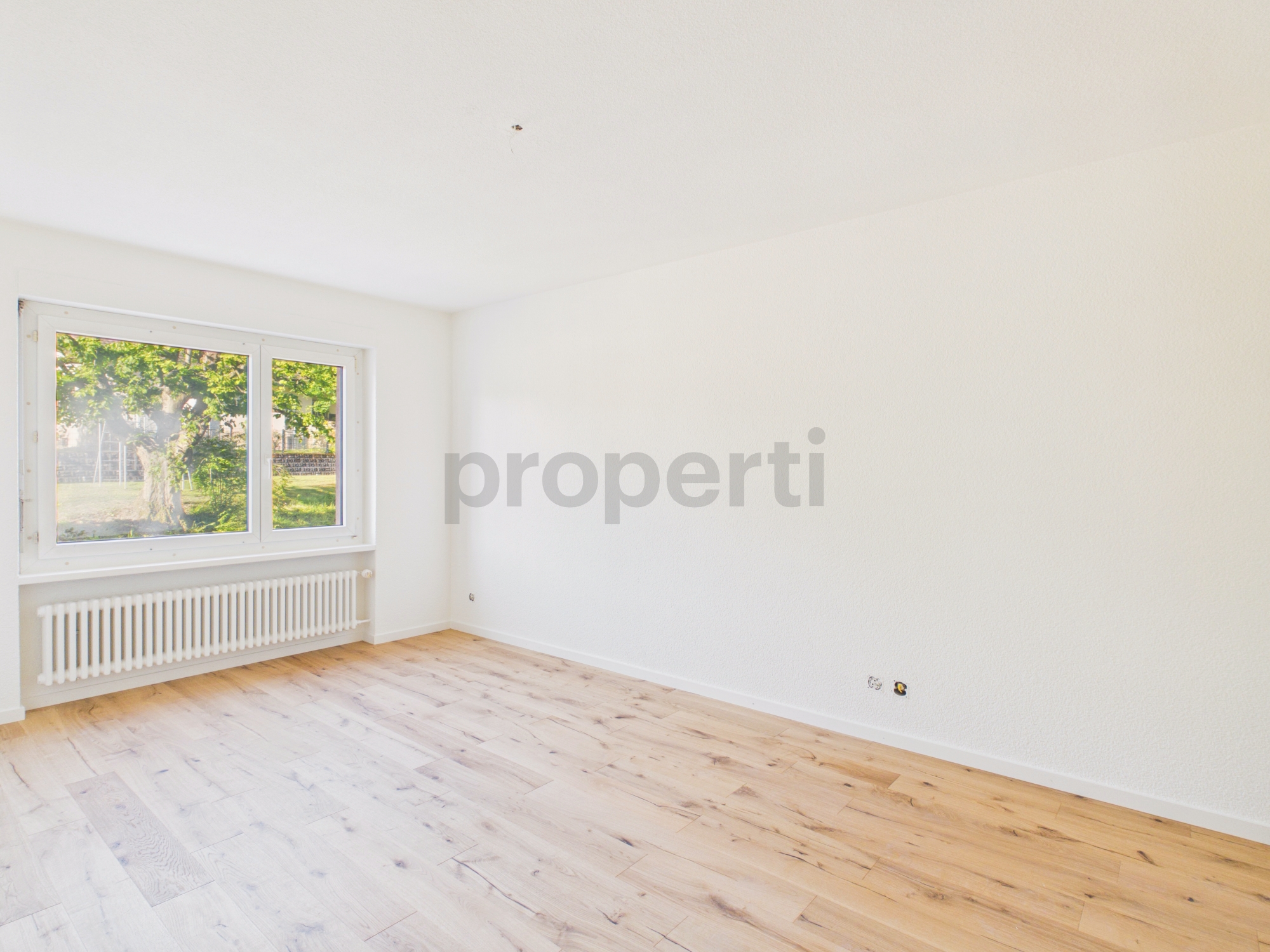 Heller leerer Raum mit Fenster und Parkettboden
