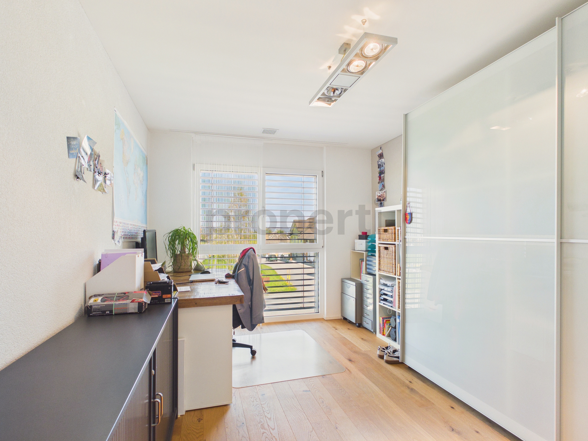 Helles Arbeitszimmer mit Schreibtisch und Schiebetürschrank