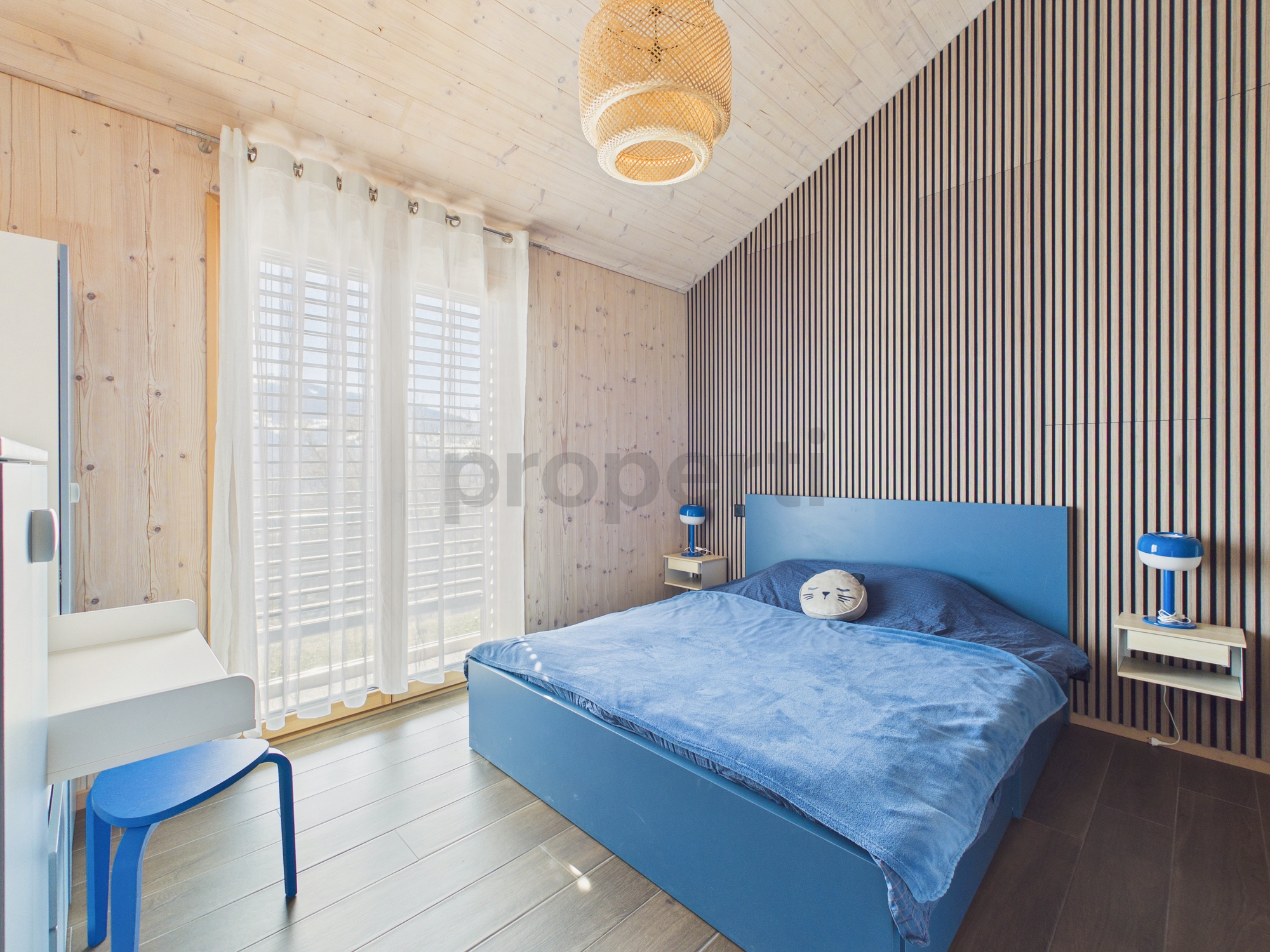 Helles Schlafzimmer mit Holzverkleidung und blauem Bett