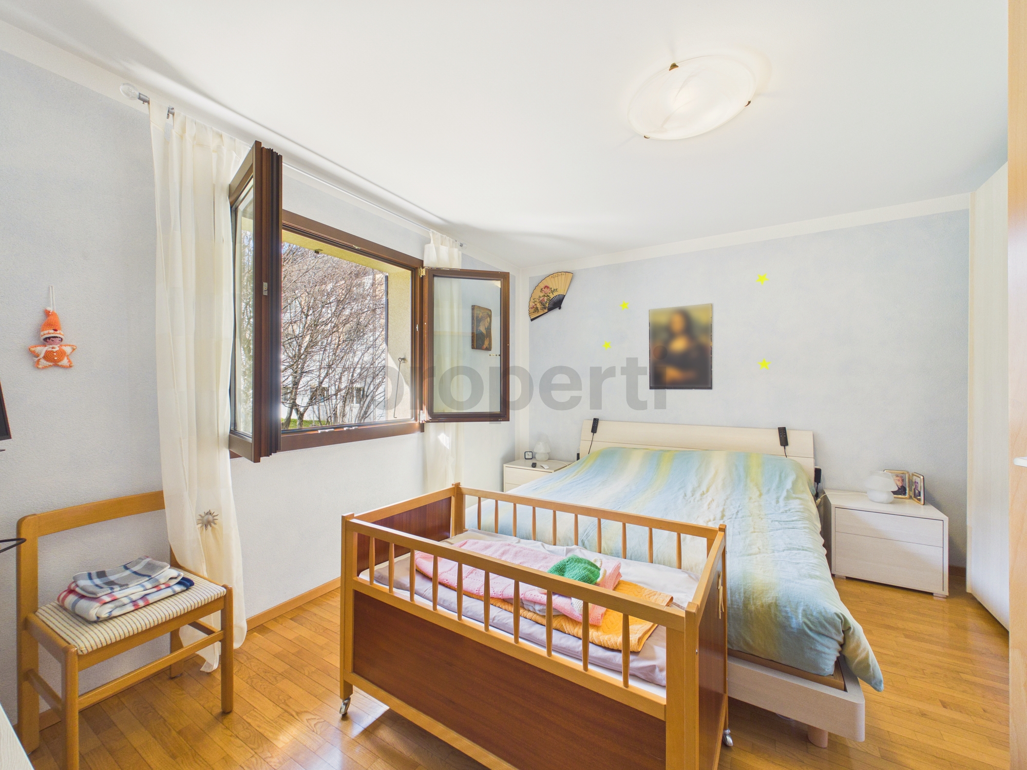 Helles Schlafzimmer mit Kinderbett und offenem Fenster