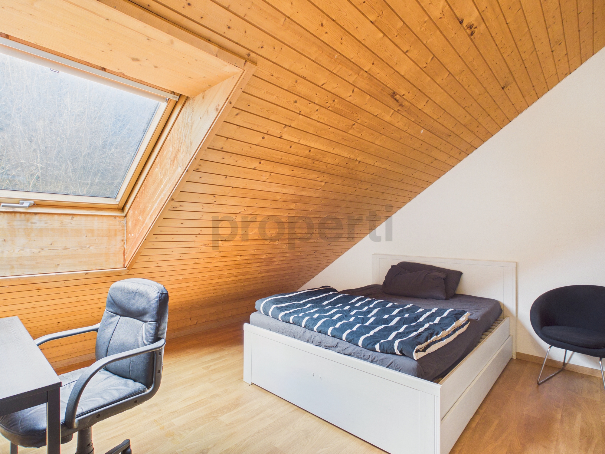 Dachzimmer mit Bett und Dachfenster