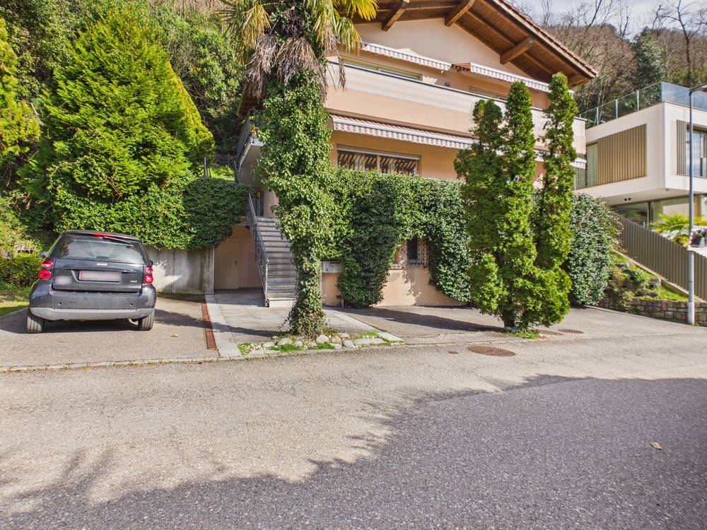 Außenansicht eines begrünten Wohnhauses mit Zufahrt