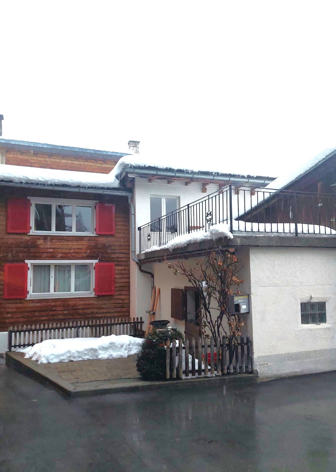 Schneebedecktes Wohnhaus mit Balkon und Holzfassade