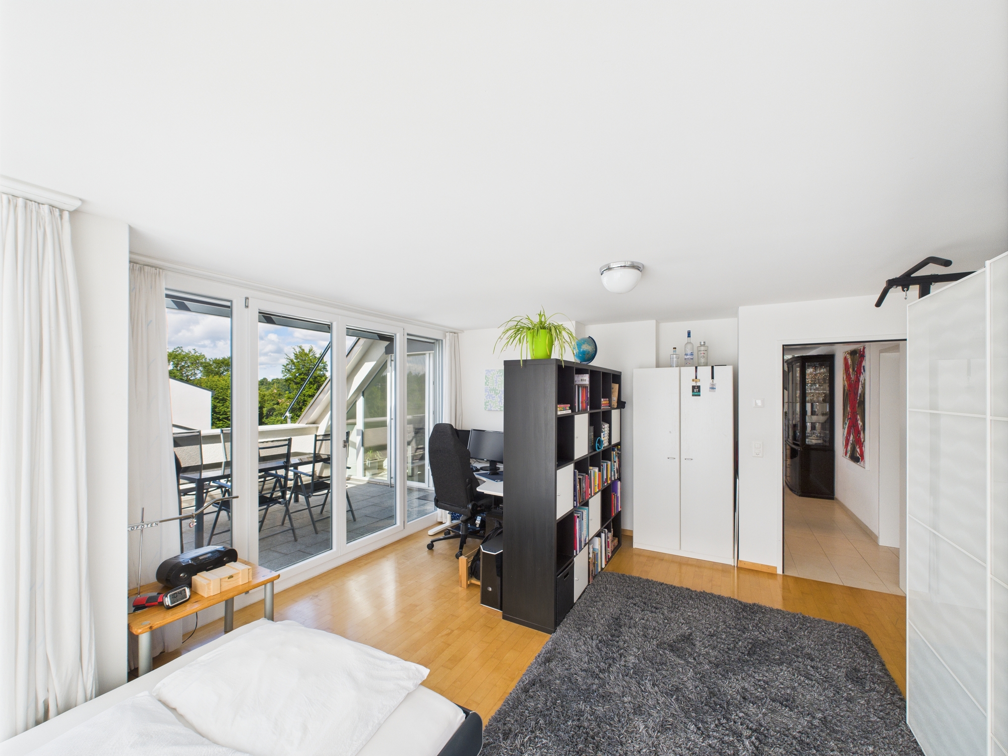 Helles Schlafzimmer mit Arbeitsplatz und Balkonzugang