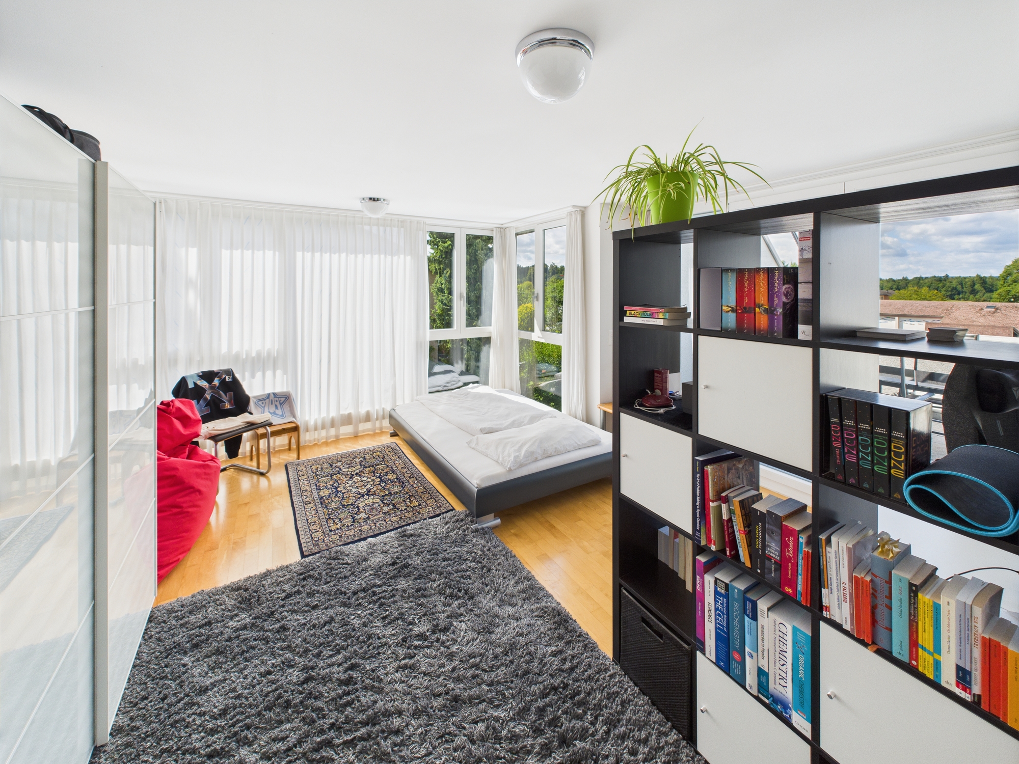 Helles Schlafzimmer mit großer Fensterfront und Regalsystem