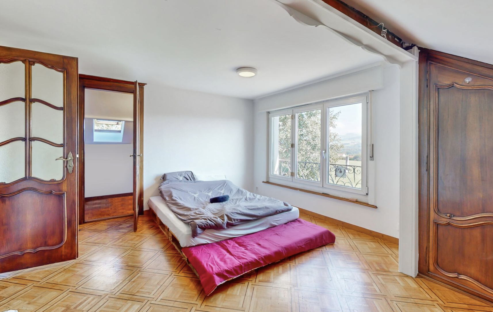 Schlafzimmer mit Parkett und großem Fenster