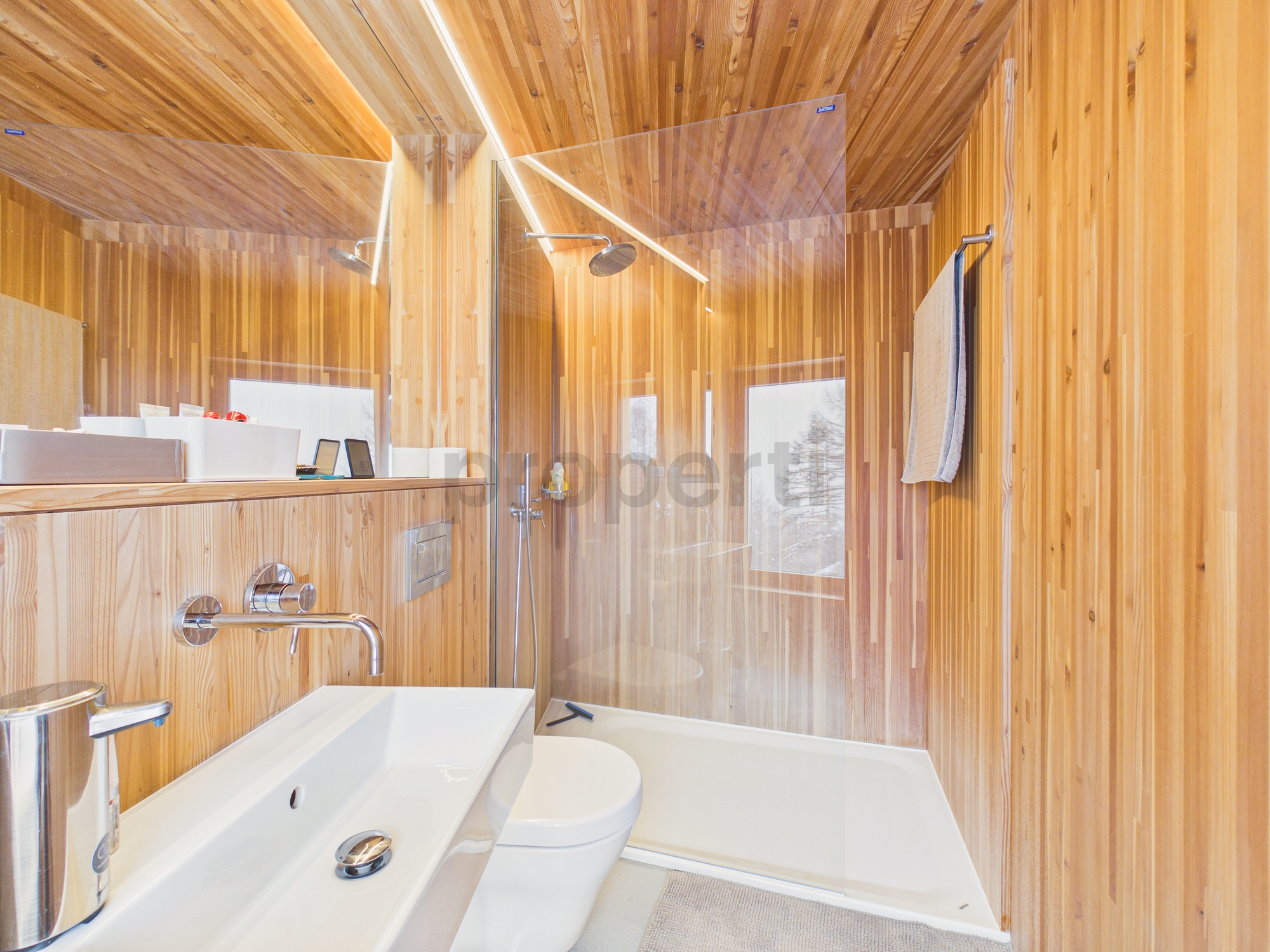 Holzverkleidetes Badezimmer mit Dusche und Waschbecken