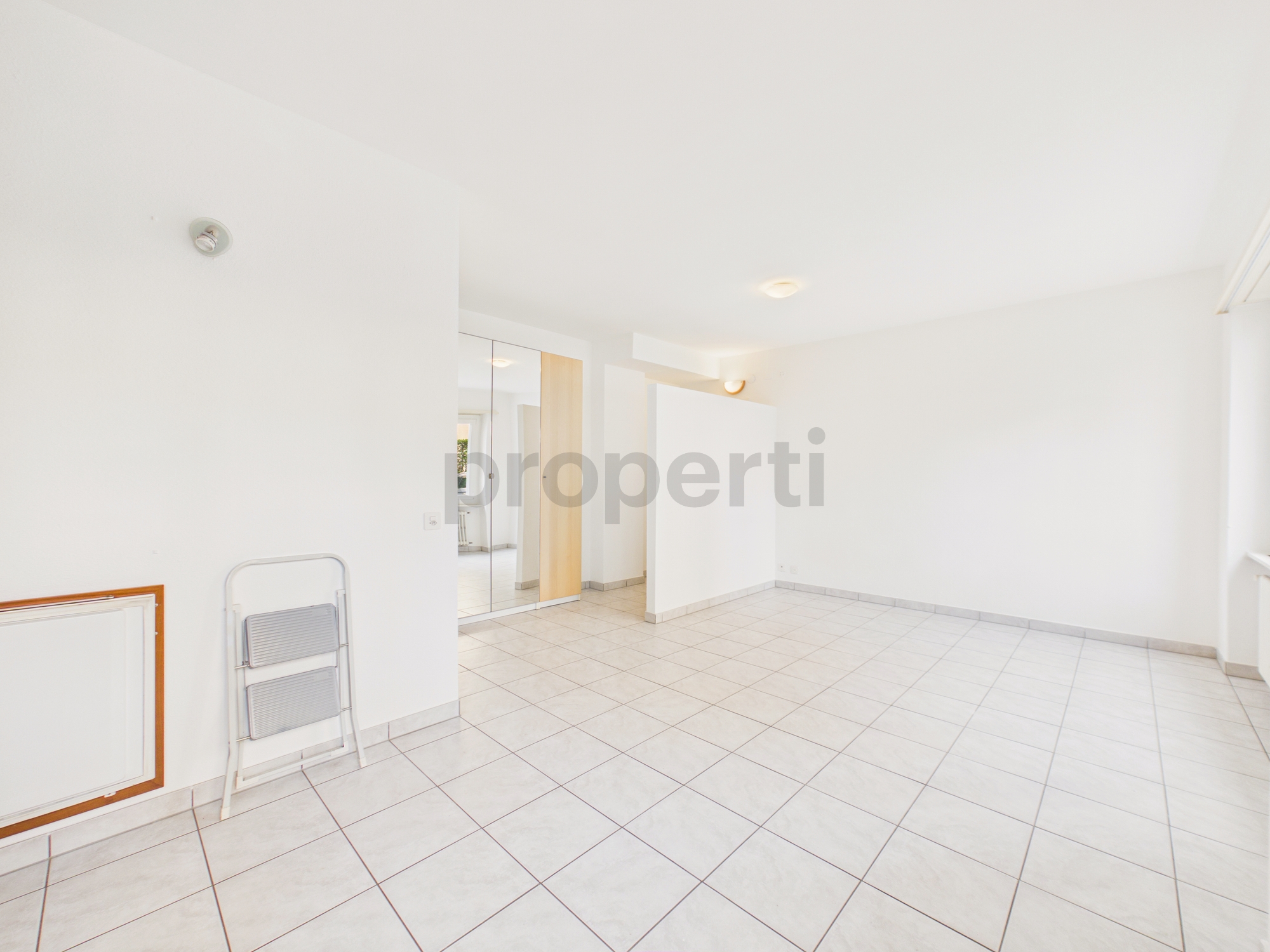 Heller leerer Wohnraum mit Fliesenboden und Einbauschrank
