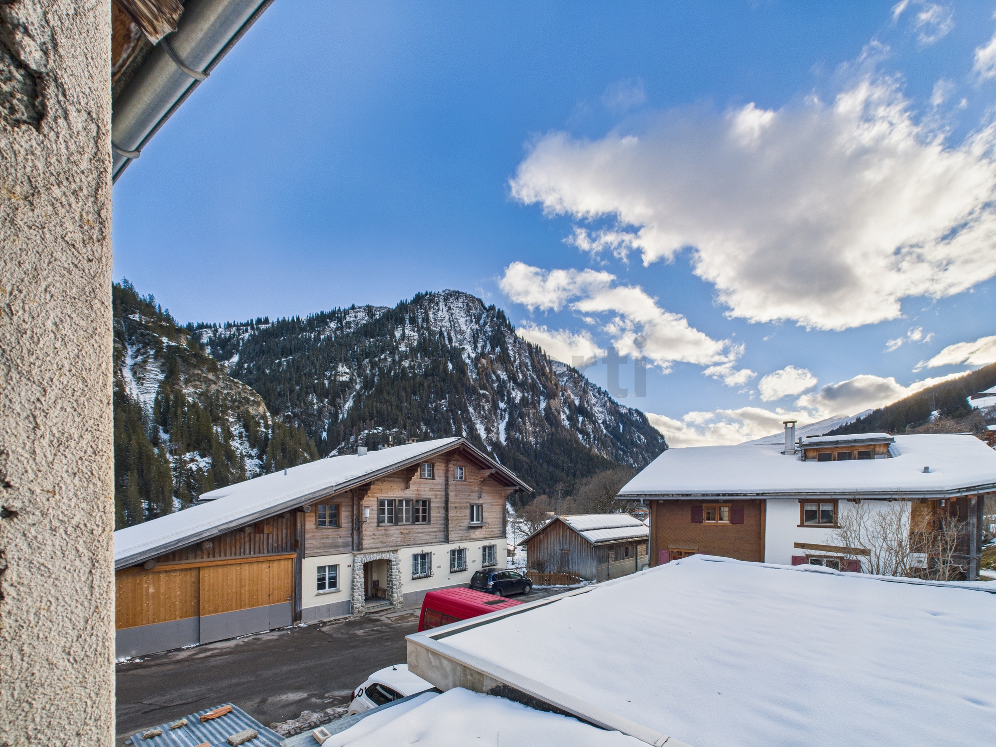 Bergdorf mit verschneiten Dächern und Alpenkulisse