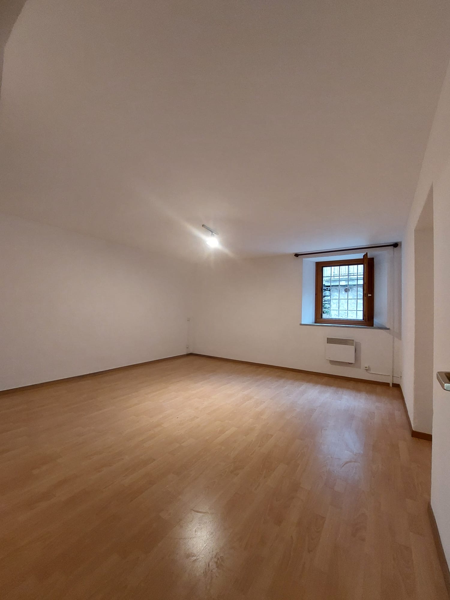 Leerer Raum mit Holzfußboden und kleinem Fenster