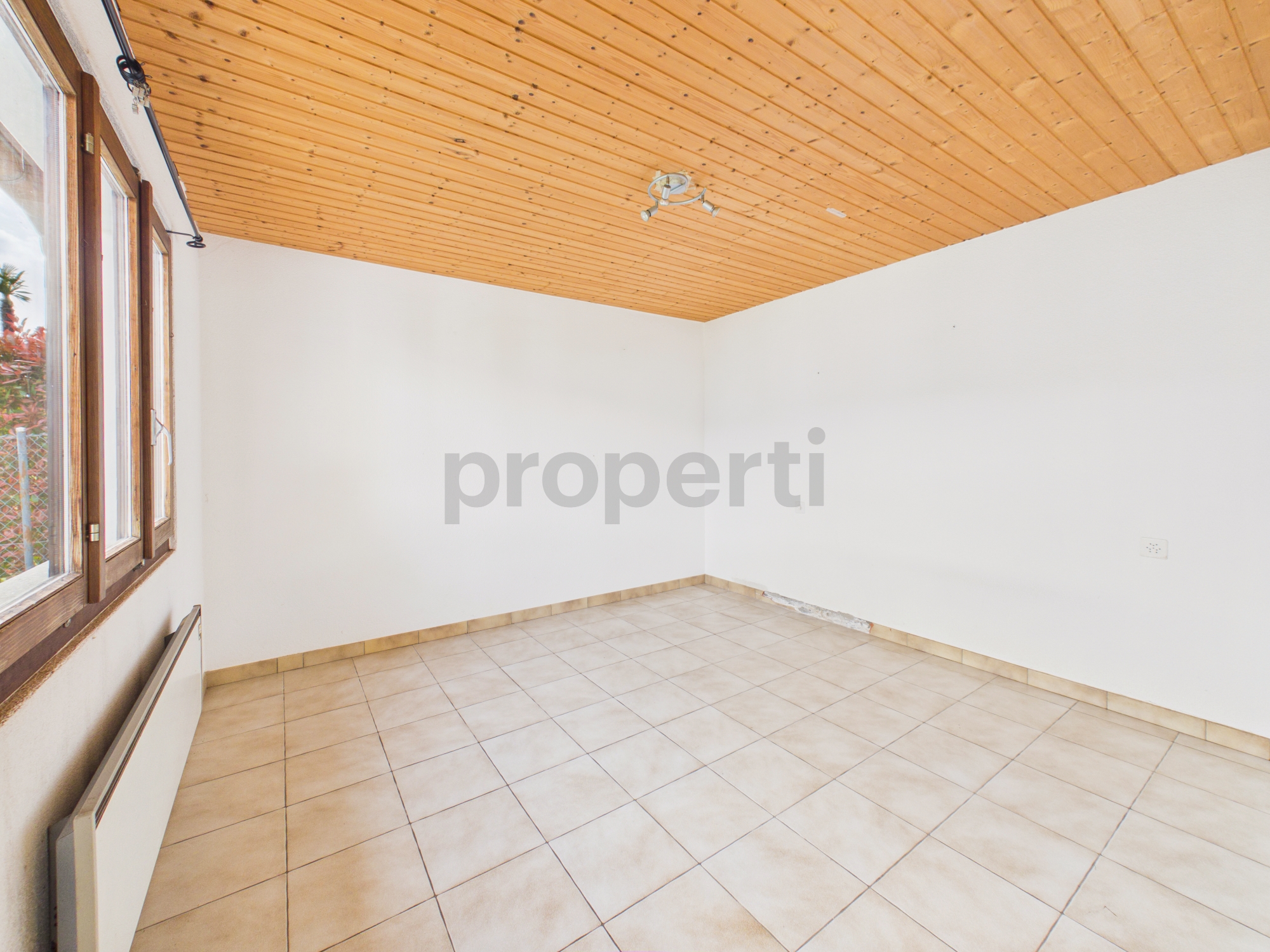 Leerer heller Raum mit Holzdecke und Fliesenboden