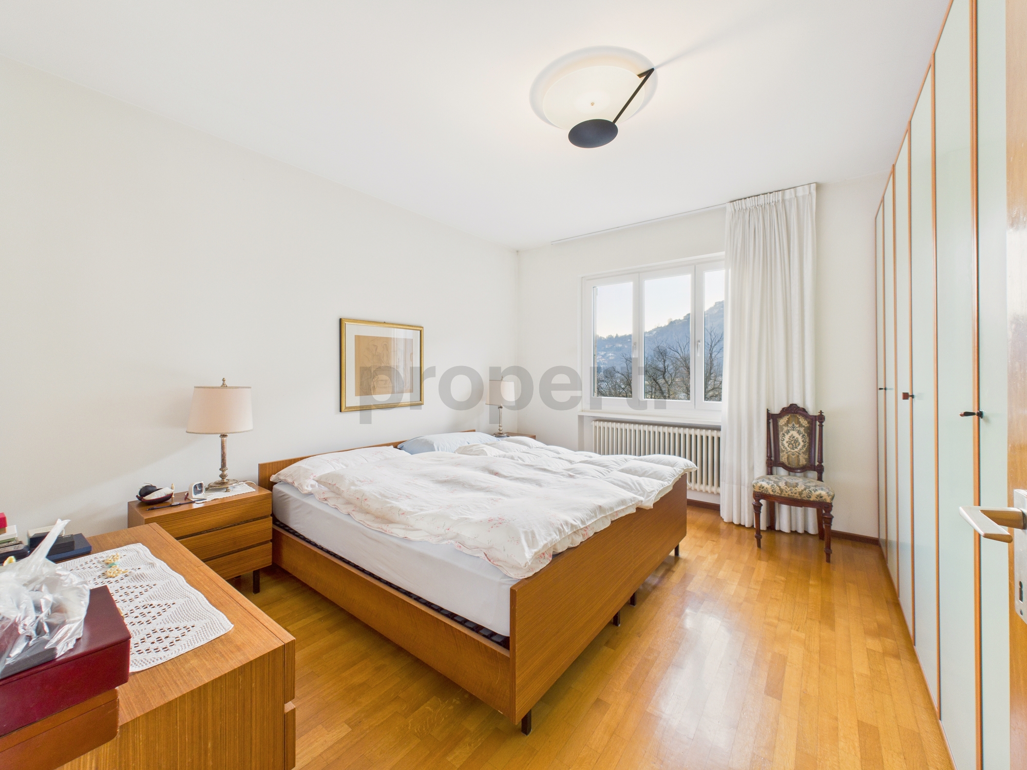 Helles Schlafzimmer mit Holzparkett und Bergblick