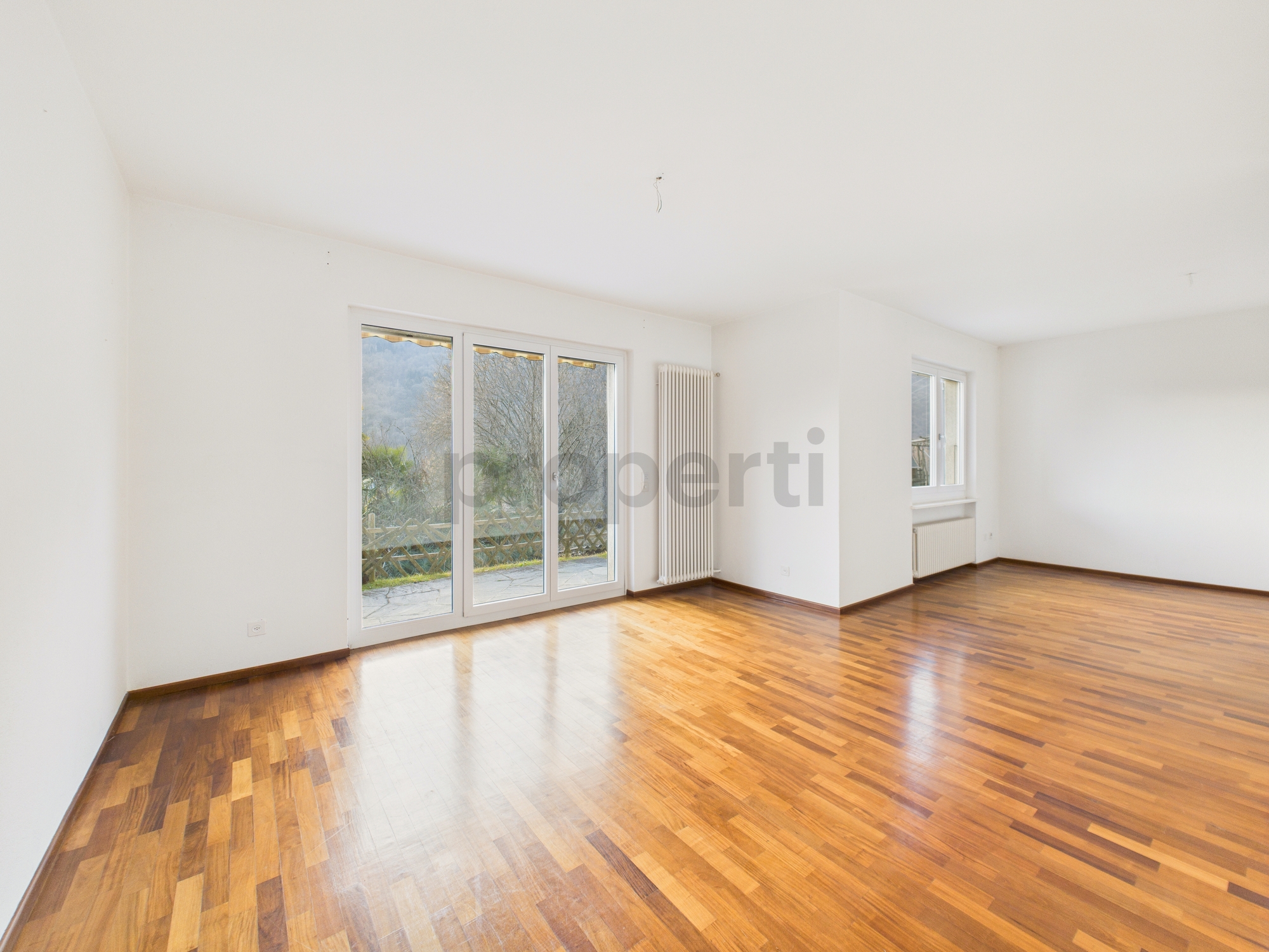 Heller leerer Wohnraum mit Parkett und Fensterfront