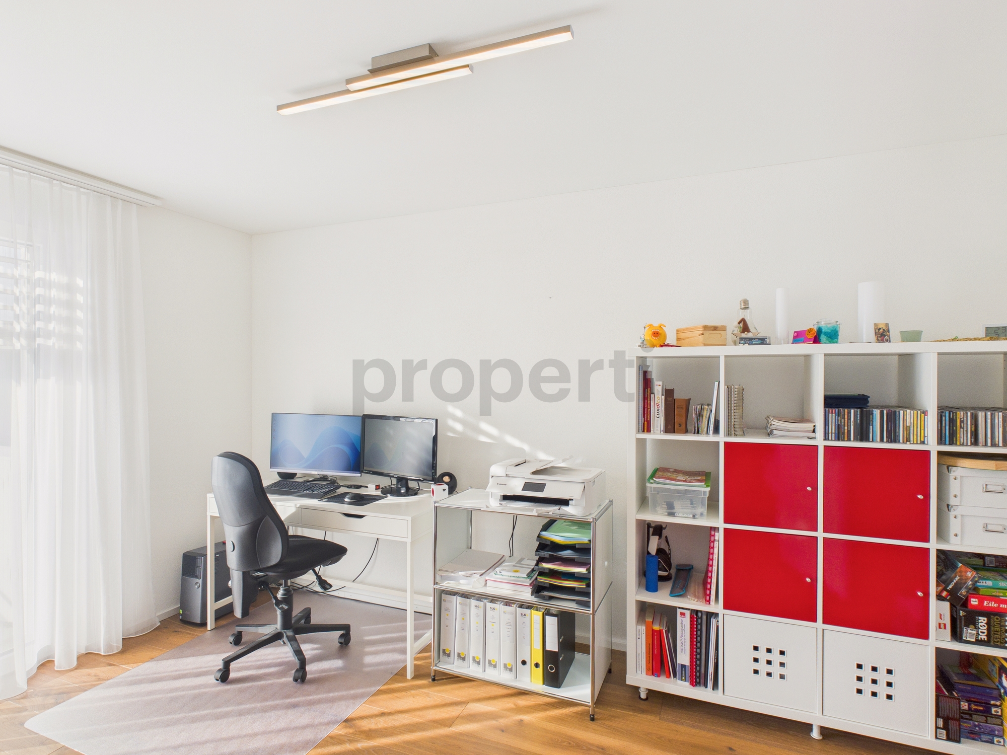 Helles Arbeitszimmer mit Schreibtisch und Regalwand