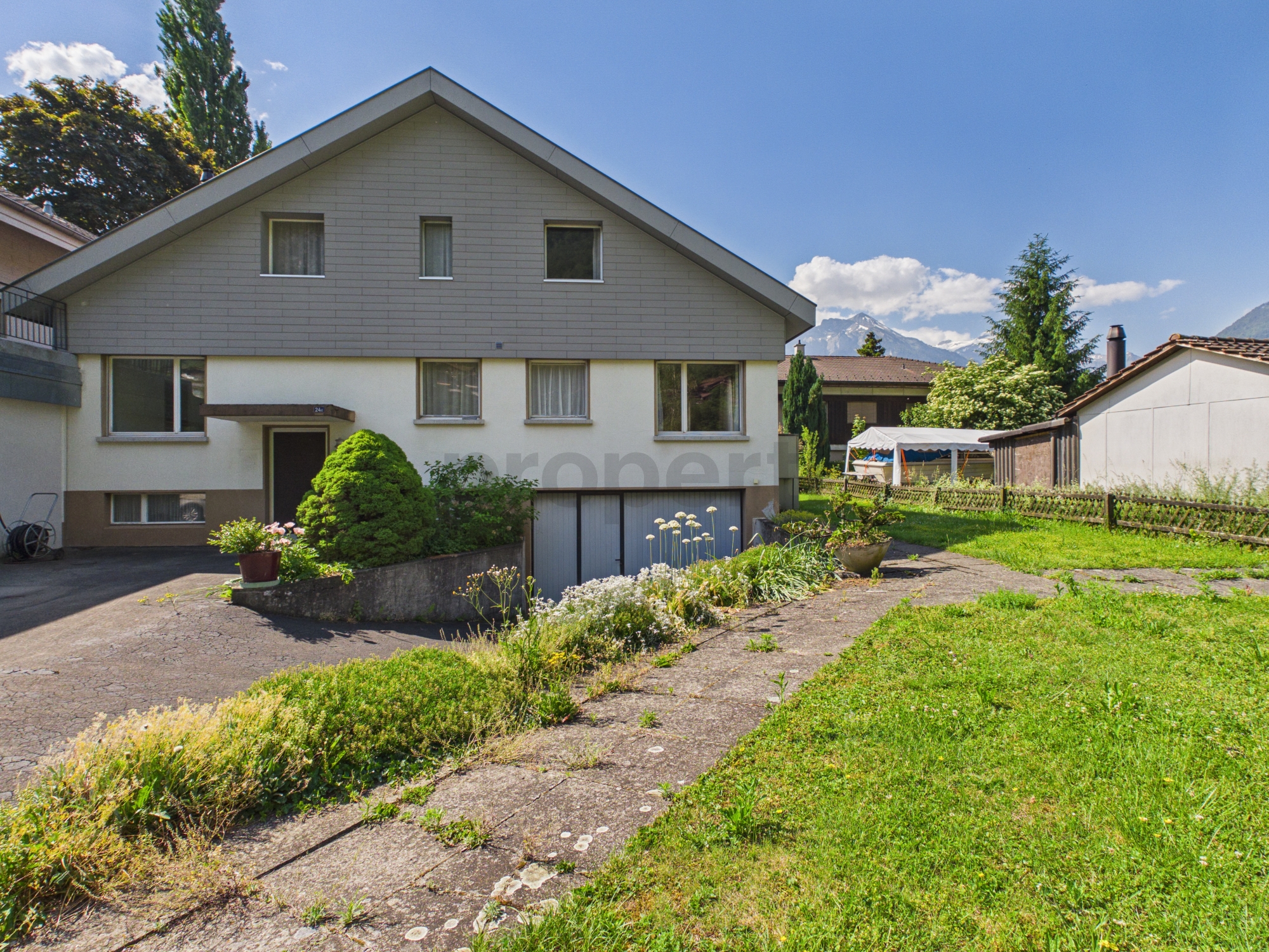 Hausansicht mit Garten und Bergkulisse