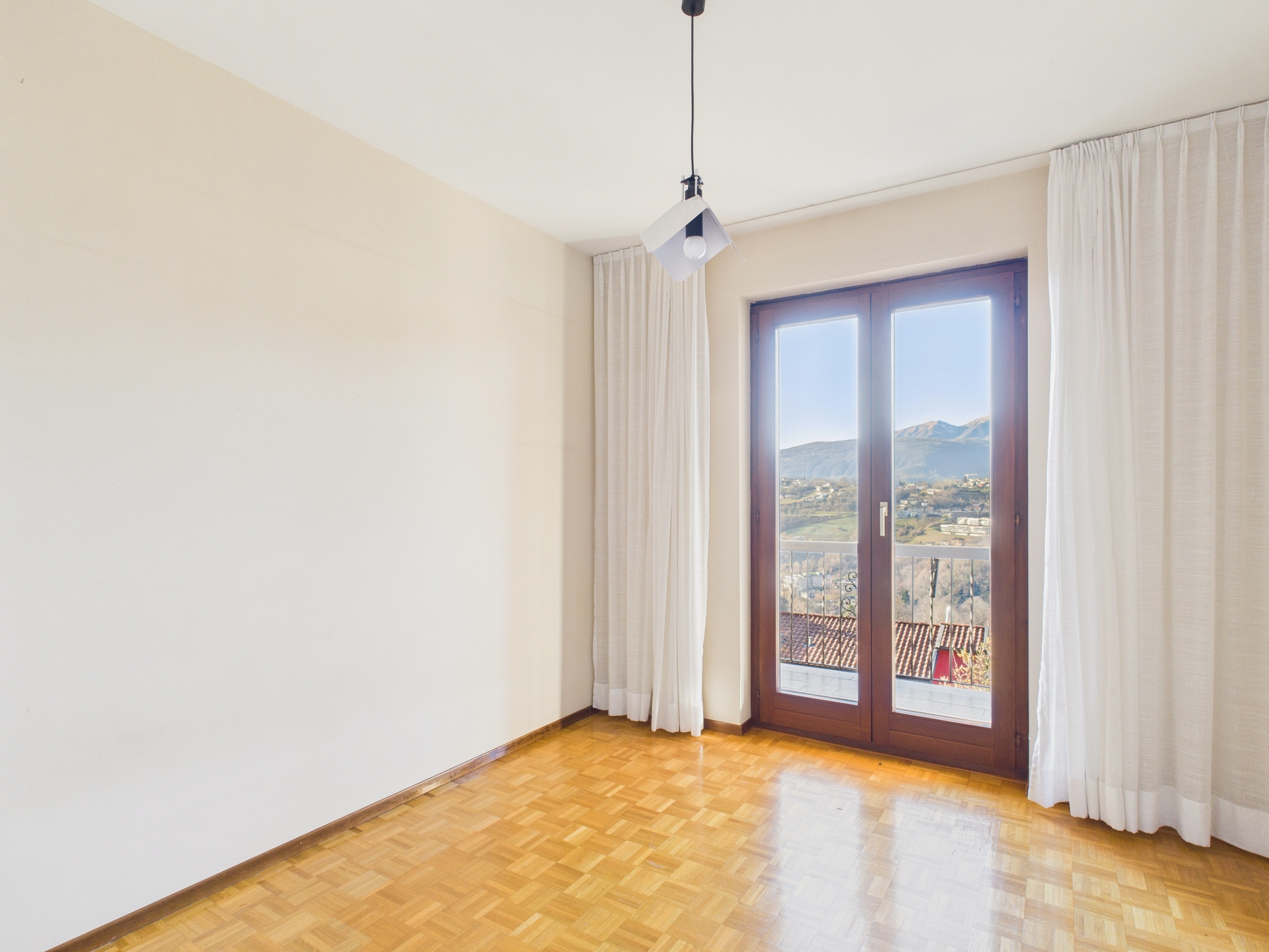 Heller leerer Raum mit Balkon- oder Terrassentür und Bergblick