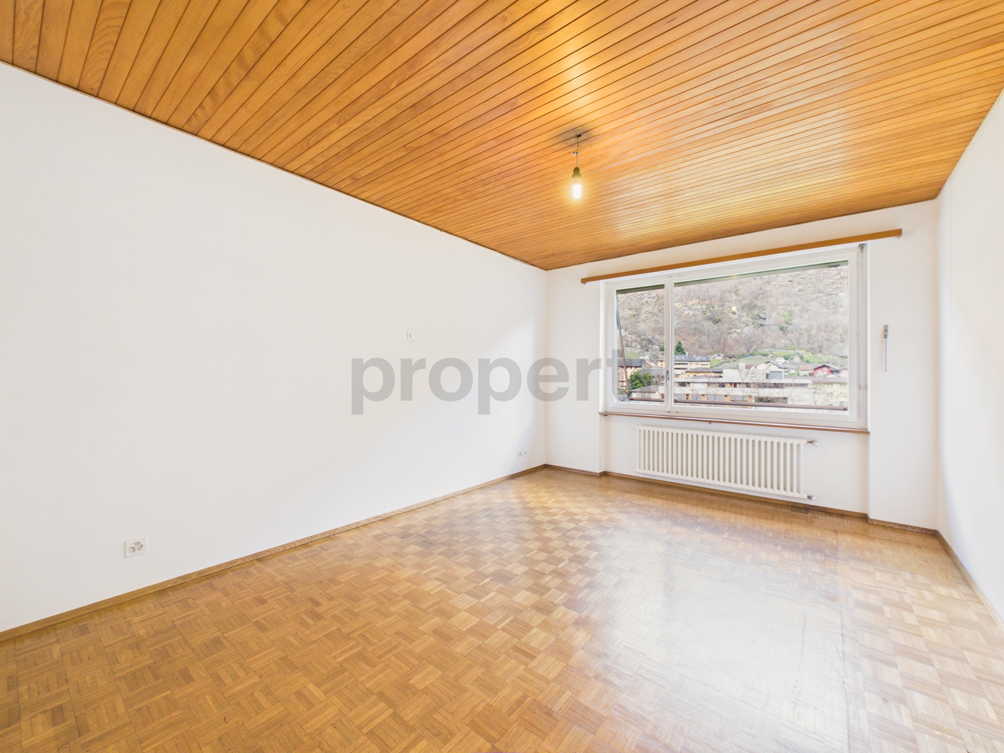 Leerer Wohnraum mit Holzdecke und Parkettboden