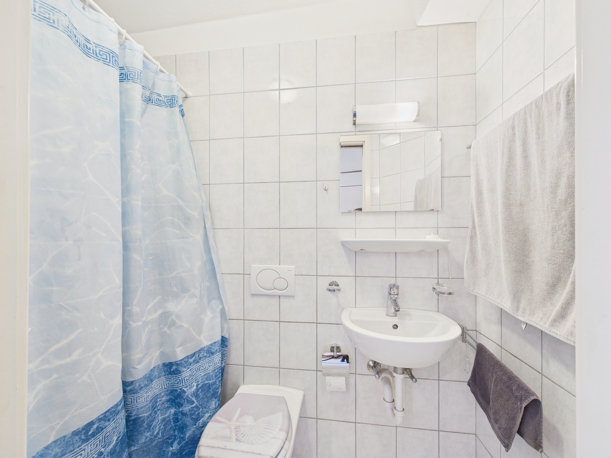 Kleines weiß gefliestes Bad mit Dusche und Waschbecken